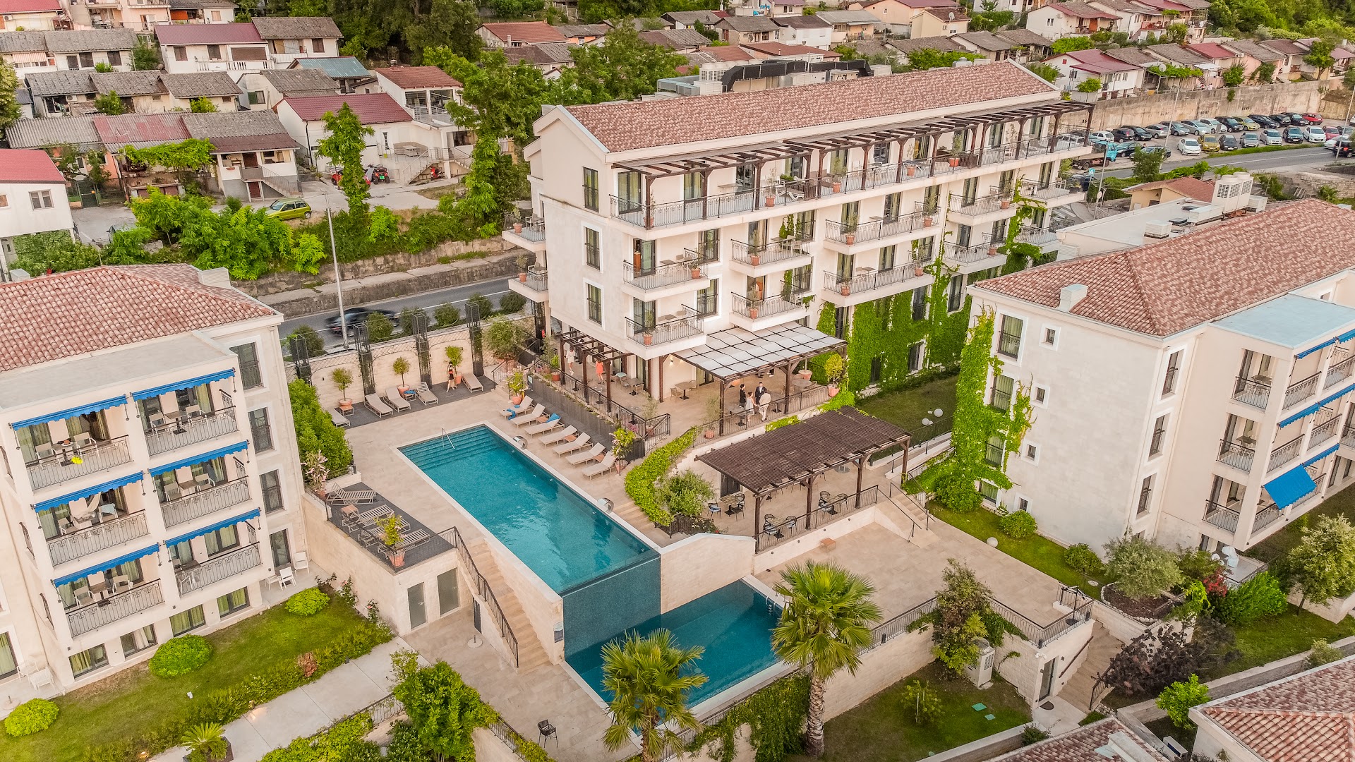 HUMA Kotor Bay Hotel & Villas divu līmeņu āra baseins ar sauļošanās krēsliem un skatu uz viesnīcas korpusiem