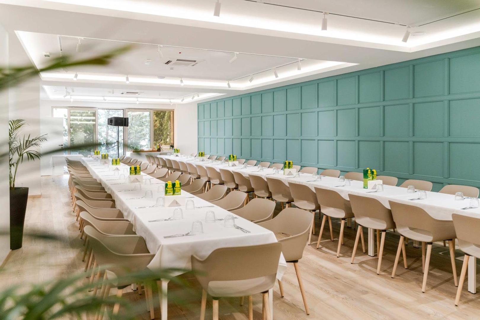 Dukley Hotel & Resort gaiša un moderna pasākumu zāle ar gariem klātiem galdiem un elegantu interjeru