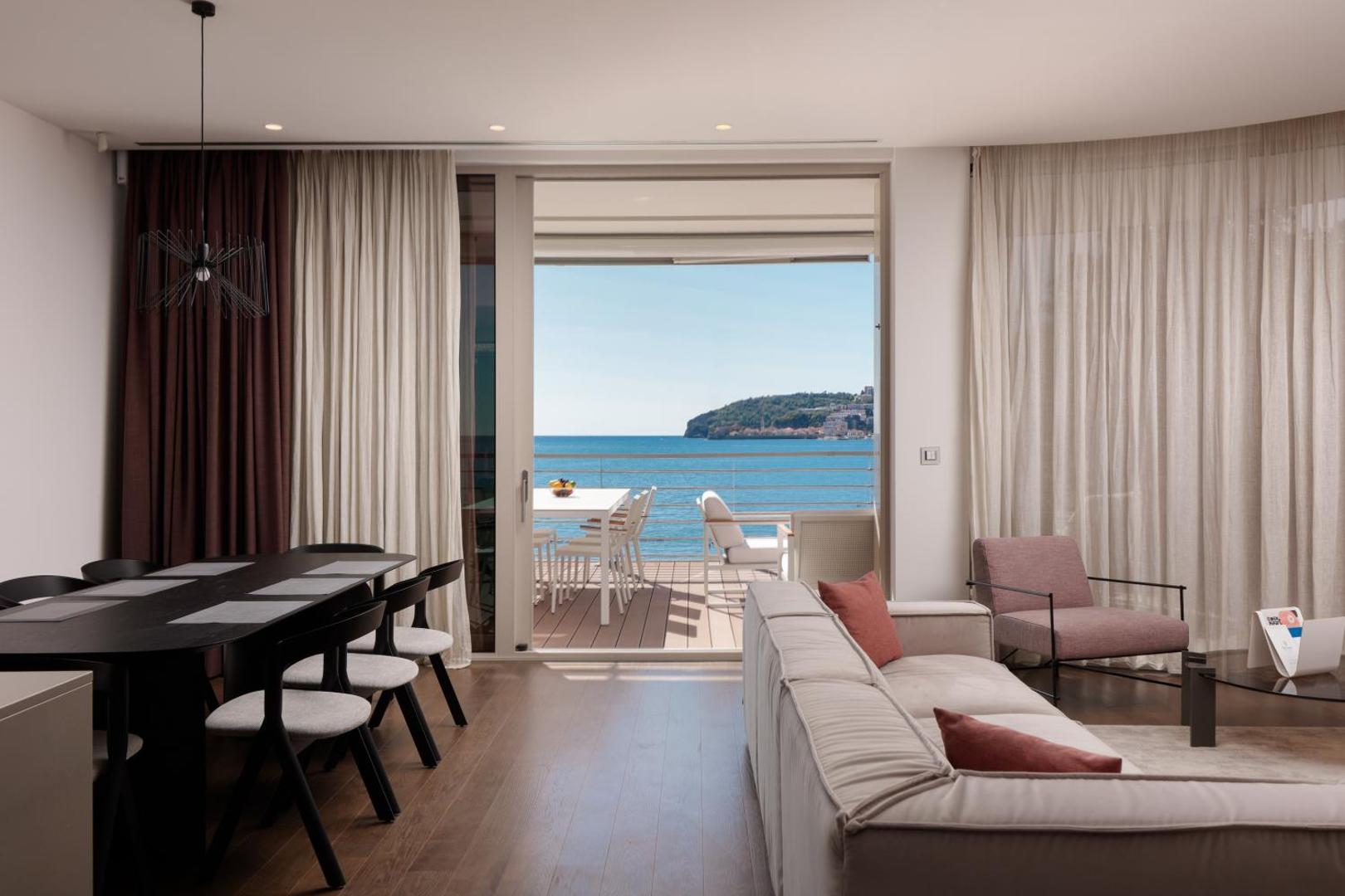 Dukley Hotel & Resort luksusa numura viesistaba ar ēdamzonu un izeju uz terasi — skats uz jūru caur lieliem logiem