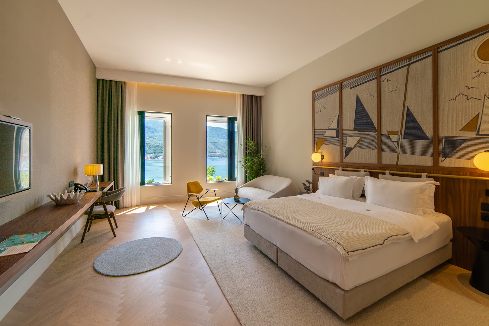 Dukley Hotel & Resort luksusa numurs ar gaišu interjeru, lielu gultu un skatu uz jūru caur logiem Budvā