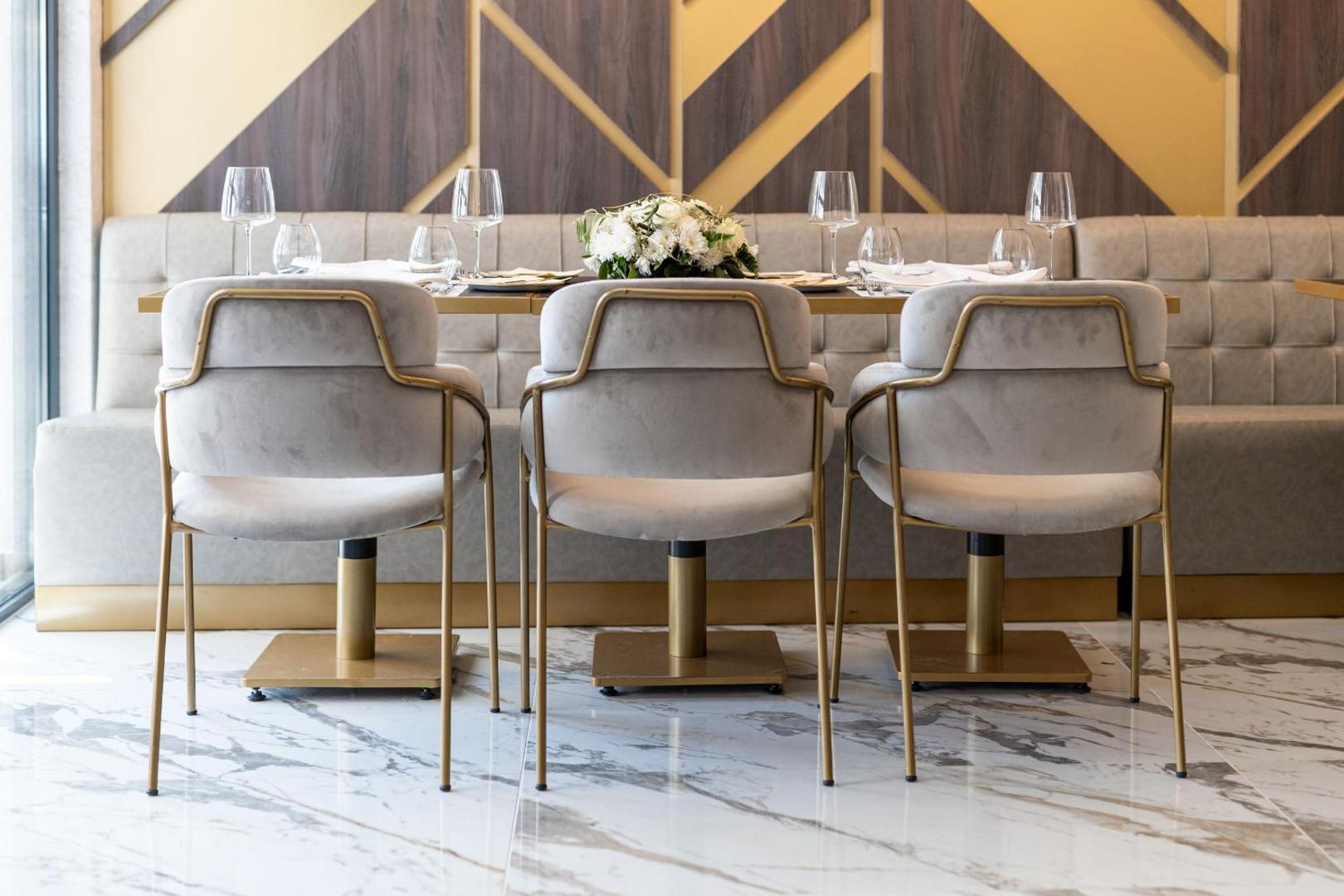 Tuvplāns Hotel Millennium by Aycon restorāna galda klājumam ar elegantiem krēsliem un ziedu dekorācijām