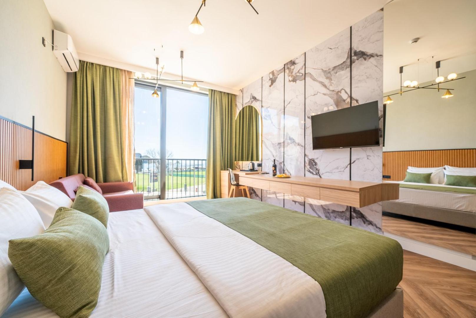Hotel Millennium by Aycon numura interjers ar skatu uz zaļo zonu caur lielajiem logiem un dīvānu