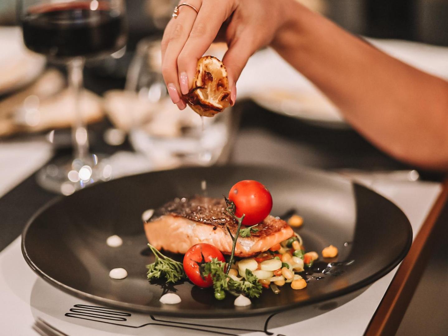 Tuvplāns ar grilētu lasi un dārzeņiem uz melna šķīvja Hotel Millennium by Aycon restorānā, Budvā