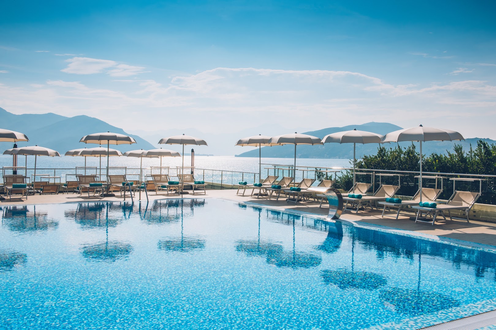 Iberostar Herceg Novi āra baseins ar skatu uz Adrijas jūru Melnkalnē — atpūtas zona ar saulessargiem un zviļņiem piekrastē