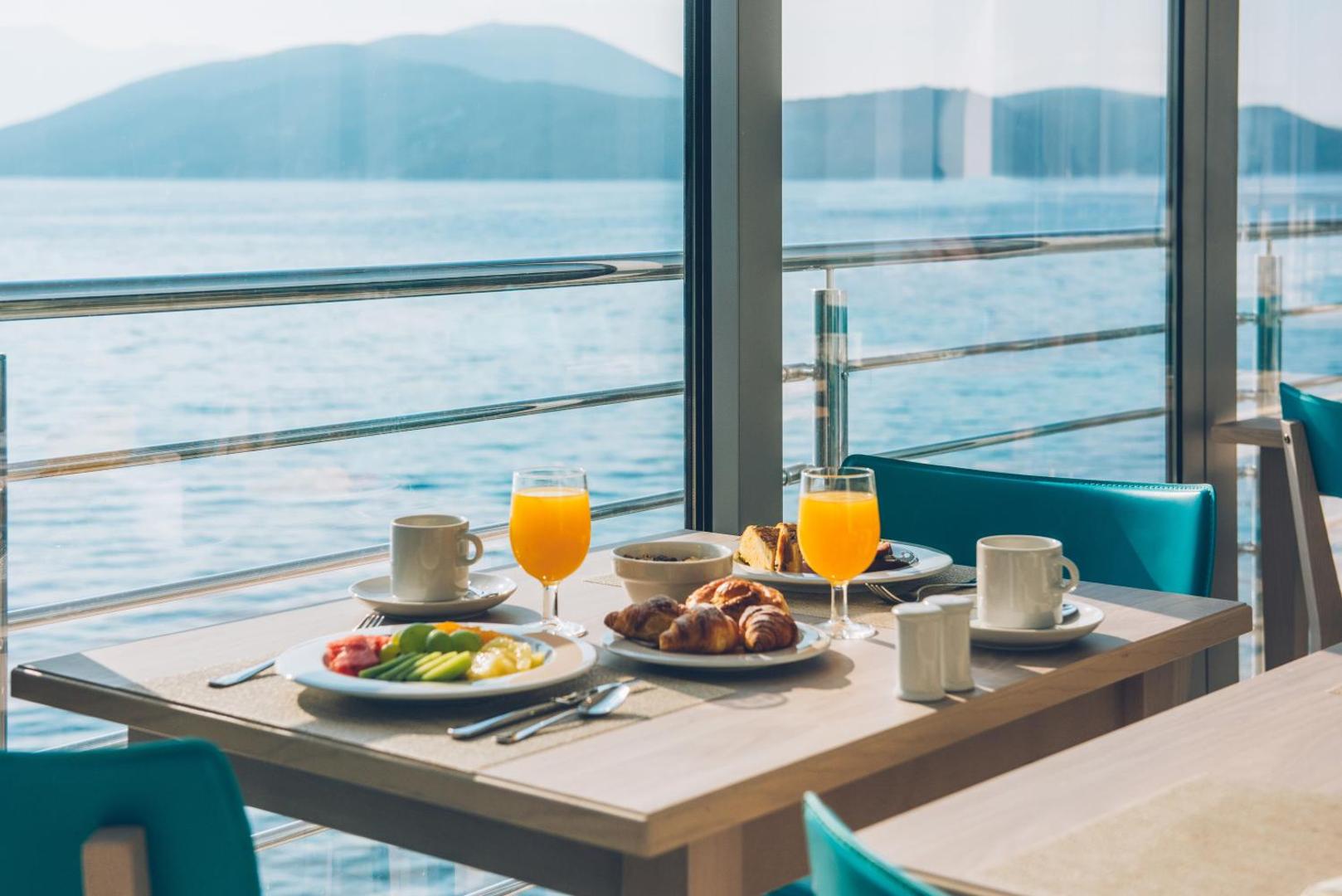 Brokastu galds Iberostar Herceg Novi restorānā ar skatu uz jūru, svaigiem augļiem, kruasāniem un apelsīnu sulu