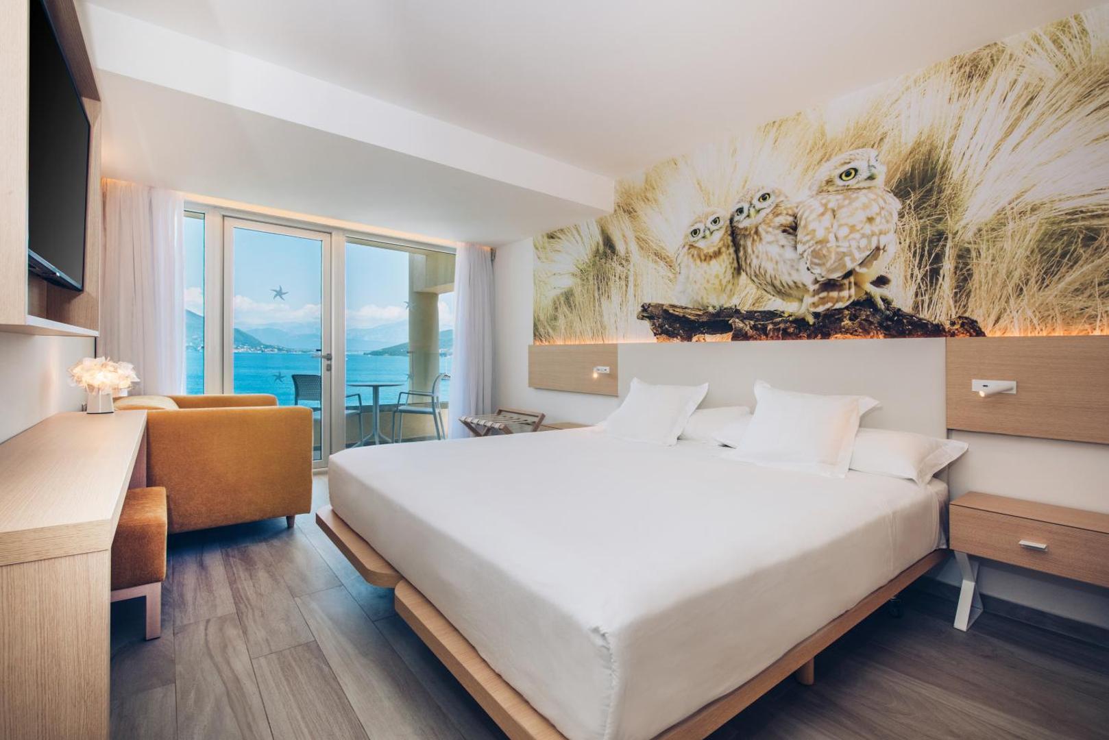 Iberostar Herceg Novi moderns viesnīcas numurs ar gaišu interjeru, lielu gultu un balkonu ar skatu uz jūru