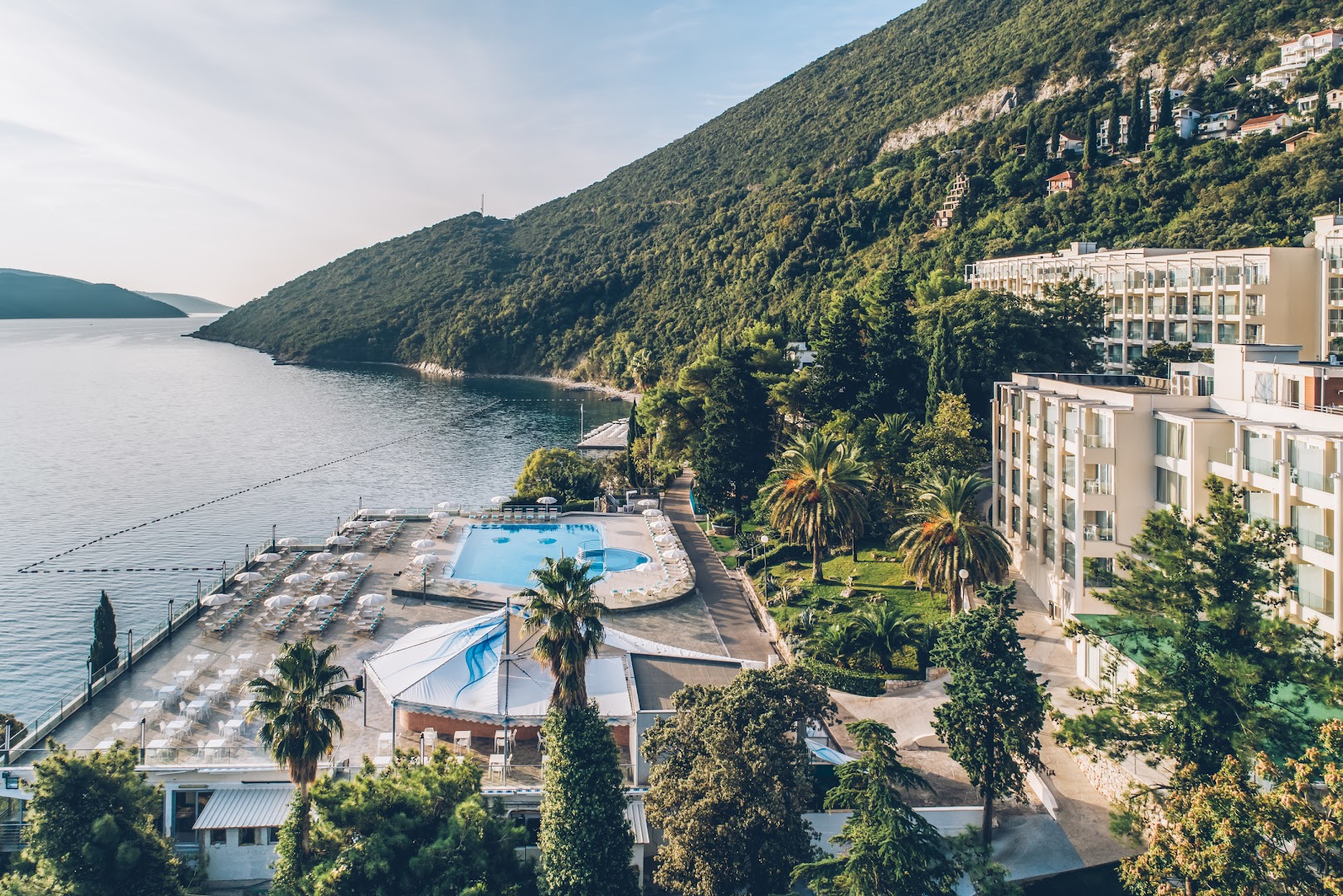 Iberostar Herceg Novi skats no augšas uz āra baseinu, sauļošanās terasi un viesnīcas korpusiem pie Adrijas jūras līča Melnkalnē