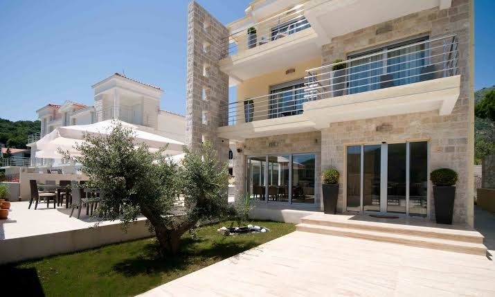 Boutique Hotel & Spa Casa del Mare āra terase ar galdiem, saulessargiem un olīvkoku pie viesnīcas akmens ēkas