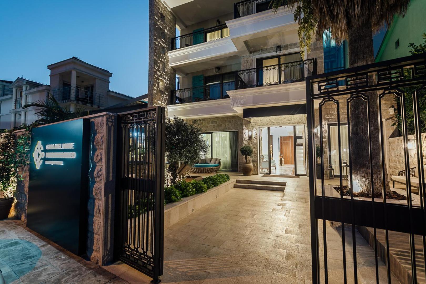 Boutique Hotel & Spa Casa del Mare ieeja un pagalms krēslas stundā ar izgaismotu viesnīcas nosaukumu un olīvkoku