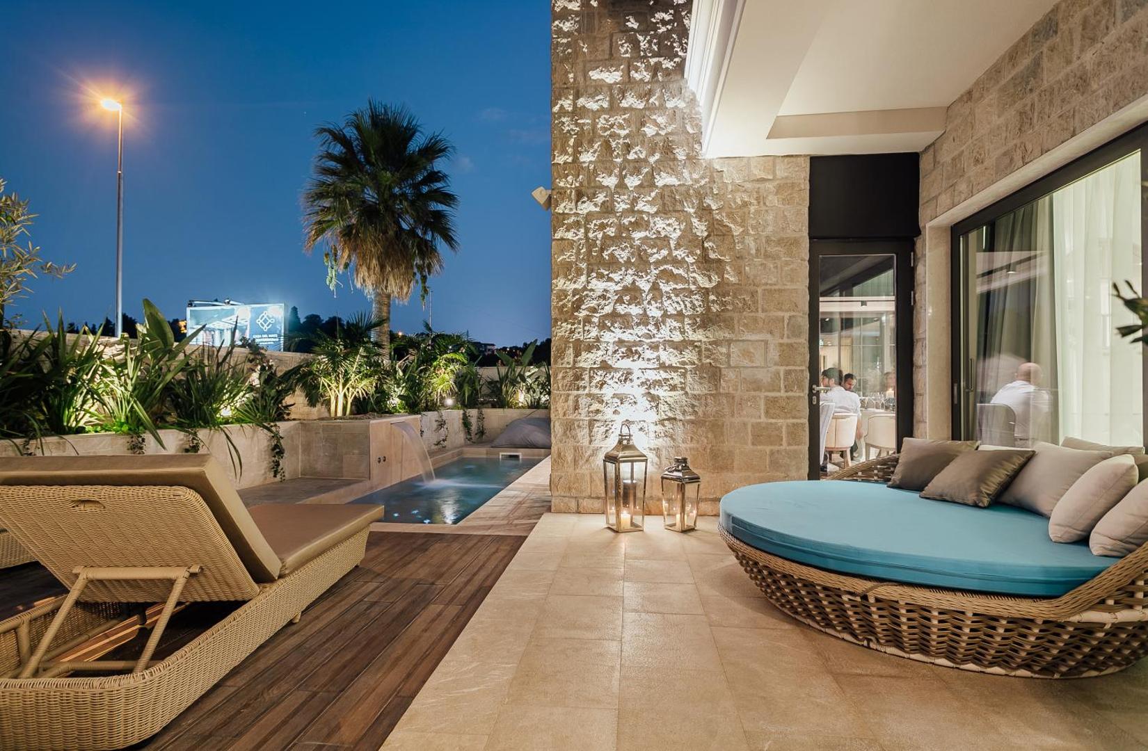Boutique Hotel & Spa Casa del Mare luksusa terase ar apaļo atpūtas sauļošanās krēslu un baseinu vakara apgaismojumā