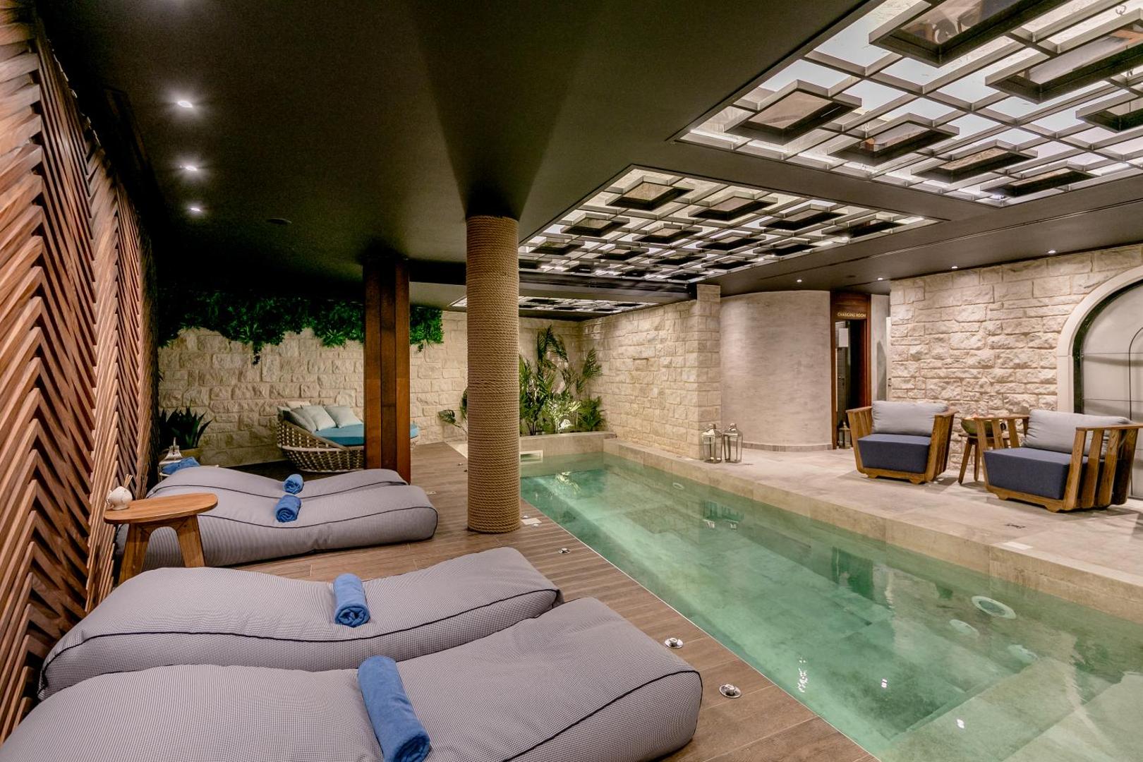 Boutique Hotel & Spa Casa del Mare iekštelpu baseins un spa zona Melnkalnē ar mīkstiem atpūtas krēsliem un akmens sienu apdari