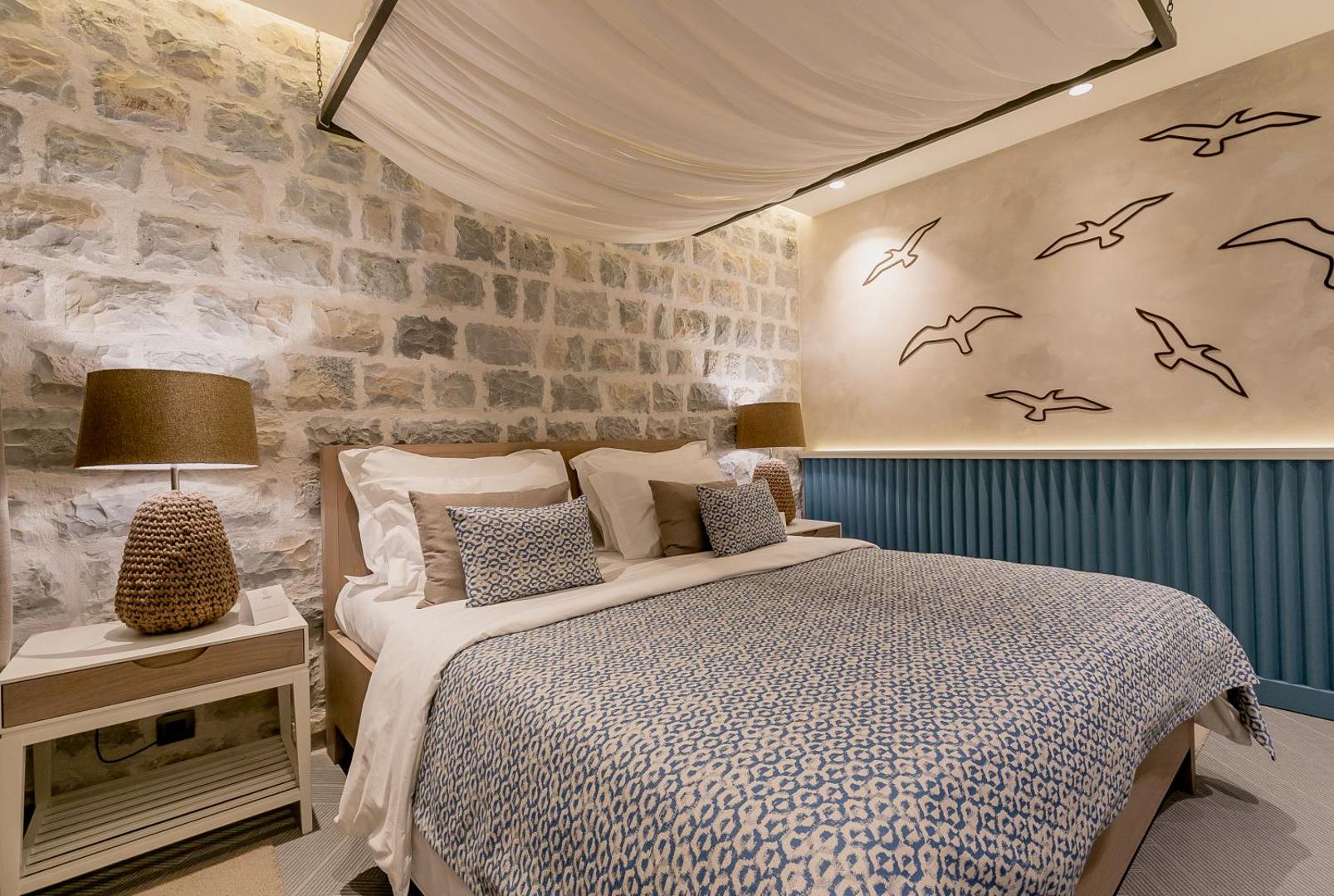 Boutique Hotel & Spa Casa del Mare numurs ar akmens sienu, baldahīnu virs gultas un dekoratīviem putnu zīmējumiem