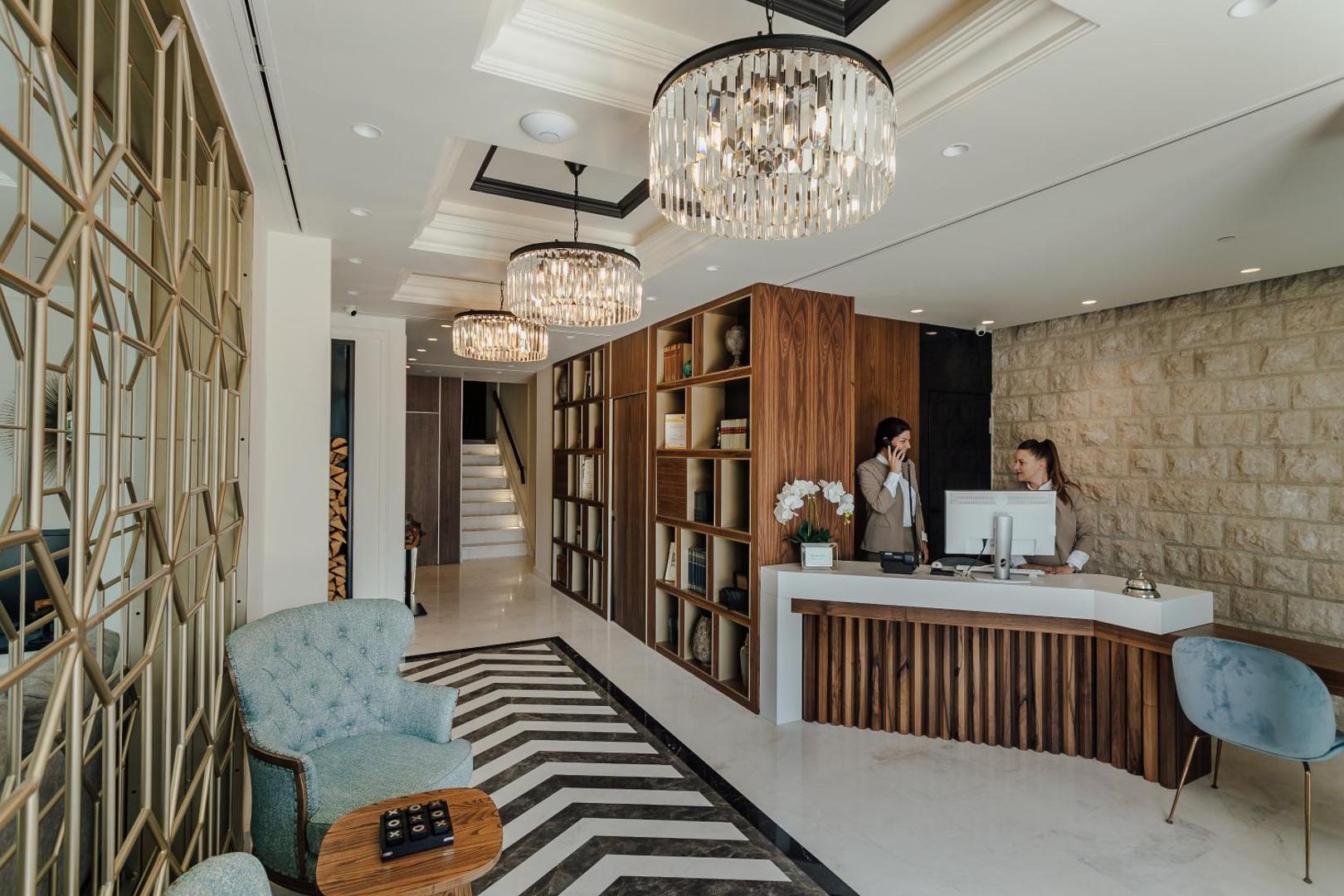 Boutique Hotel & Spa Casa del Mare modernā recepcijas zona ar koka apdari, kristāla lustrām un gaišu akmens sienu