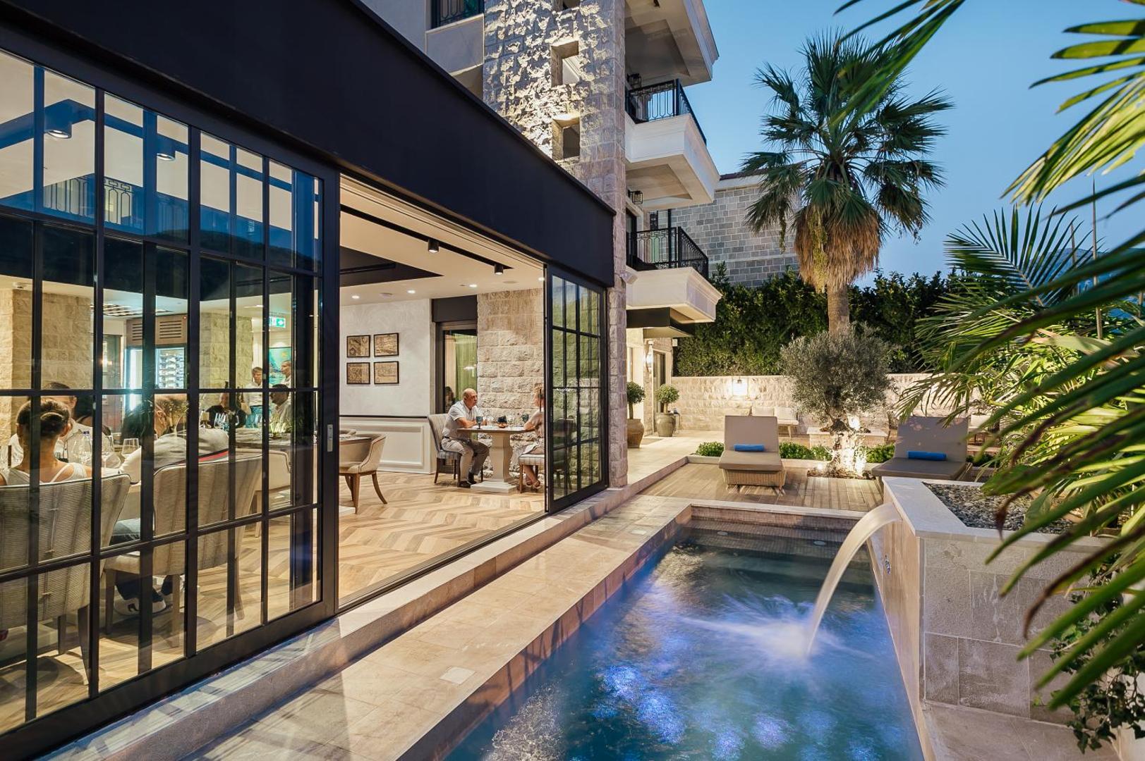 Boutique Hotel & Spa Casa del Mare restorāns un āra baseins vakarā — eleganta terase ar galdiņiem un apgaismotu fasādi