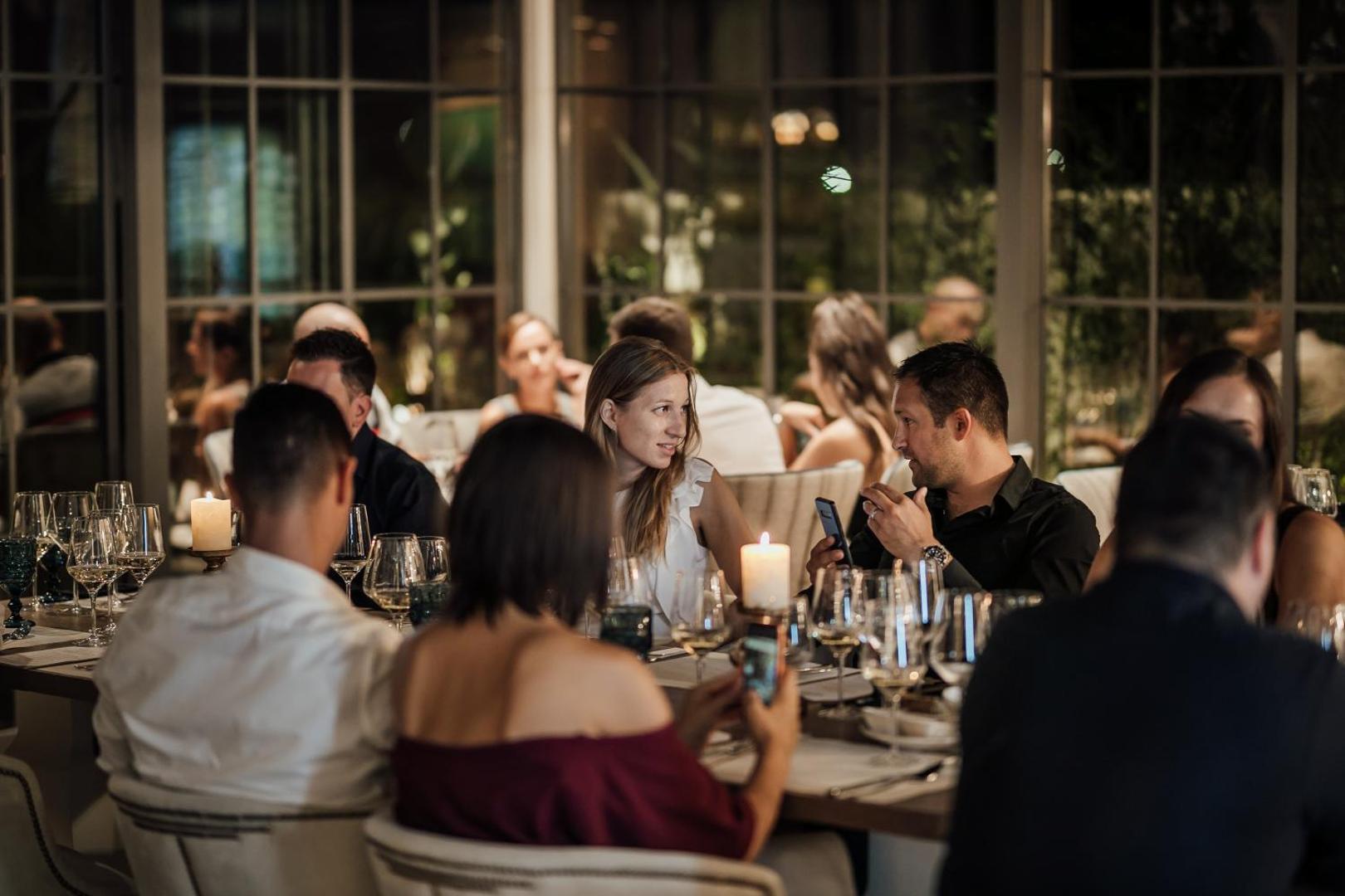 Viesi bauda vakariņas Boutique Hotel & Spa Casa del Mare restorāna iekštelpās, mājīgs apgaismojums ar svecēm un eleganta atmosfēra