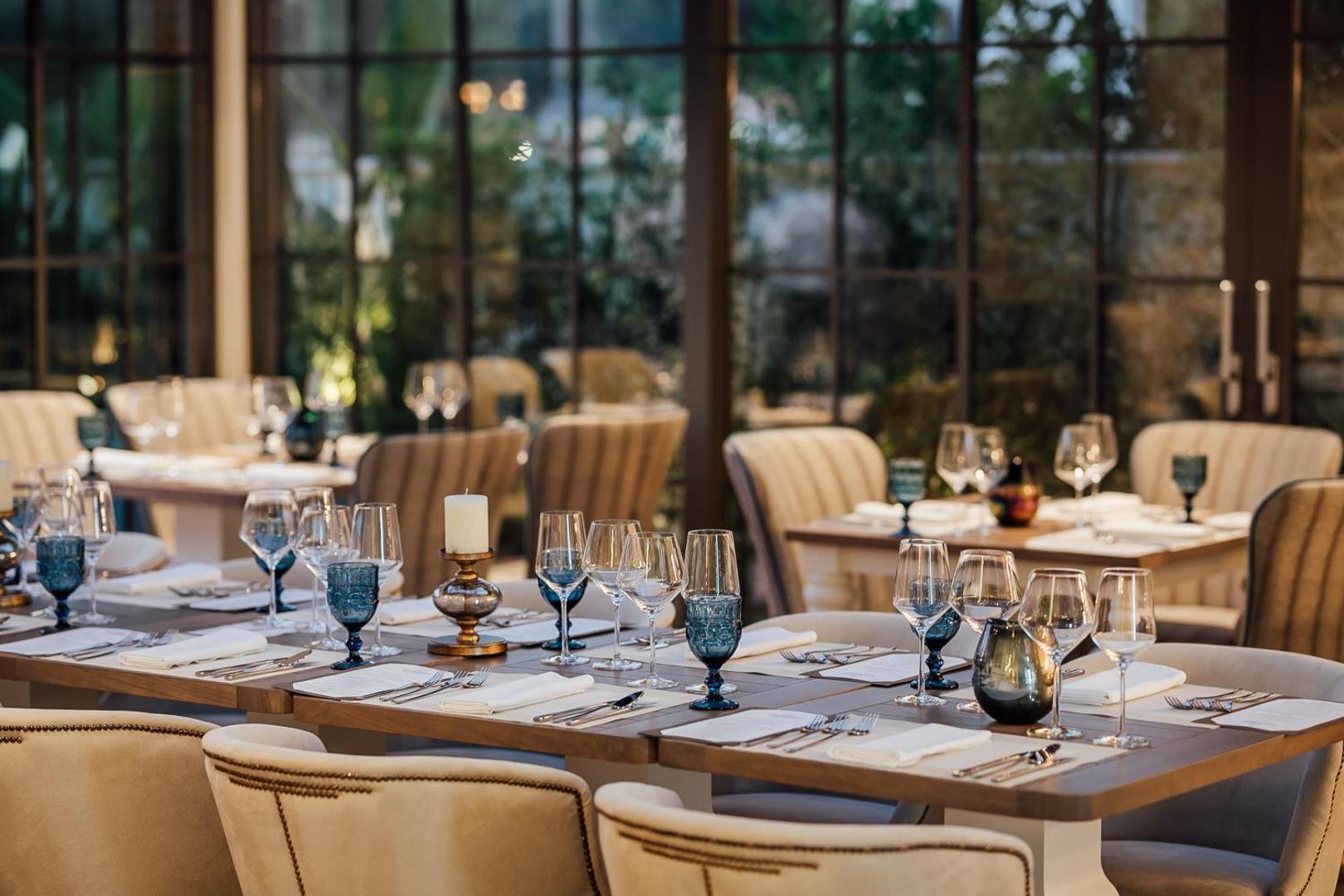 Boutique Hotel & Spa Casa del Mare restorāna iekštelpas ar eleganti klātiem galdiem, zilām glāzēm un lieliem logiem uz dārzu