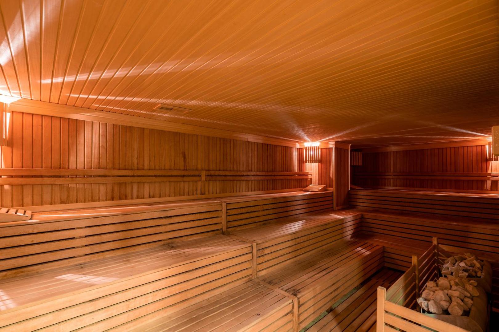 Fame Residence Kemer & Spa plašā koka sauna ar vairākiem līmeņiem un siltu apgaismojumu viesnīcas spa kompleksā