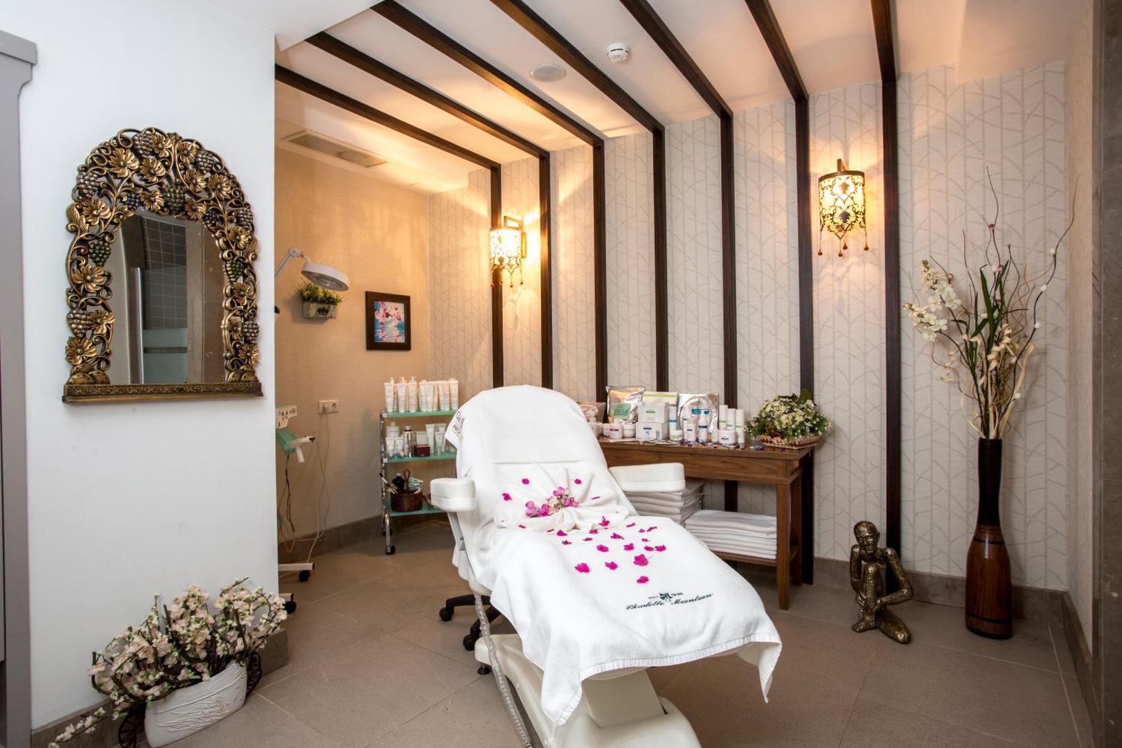 Fame Residence Kemer & Spa spa centra procedūru telpa ar masāžas galdu, dekoratīviem elementiem un kosmētikas līdzekļiem