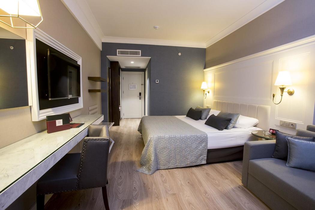Fame Residence Kemer & Spa moderns divvietīgs numurs ar gaišu koka grīdu, rakstāmgaldu, sienas TV un mīksto dīvānu atpūtai