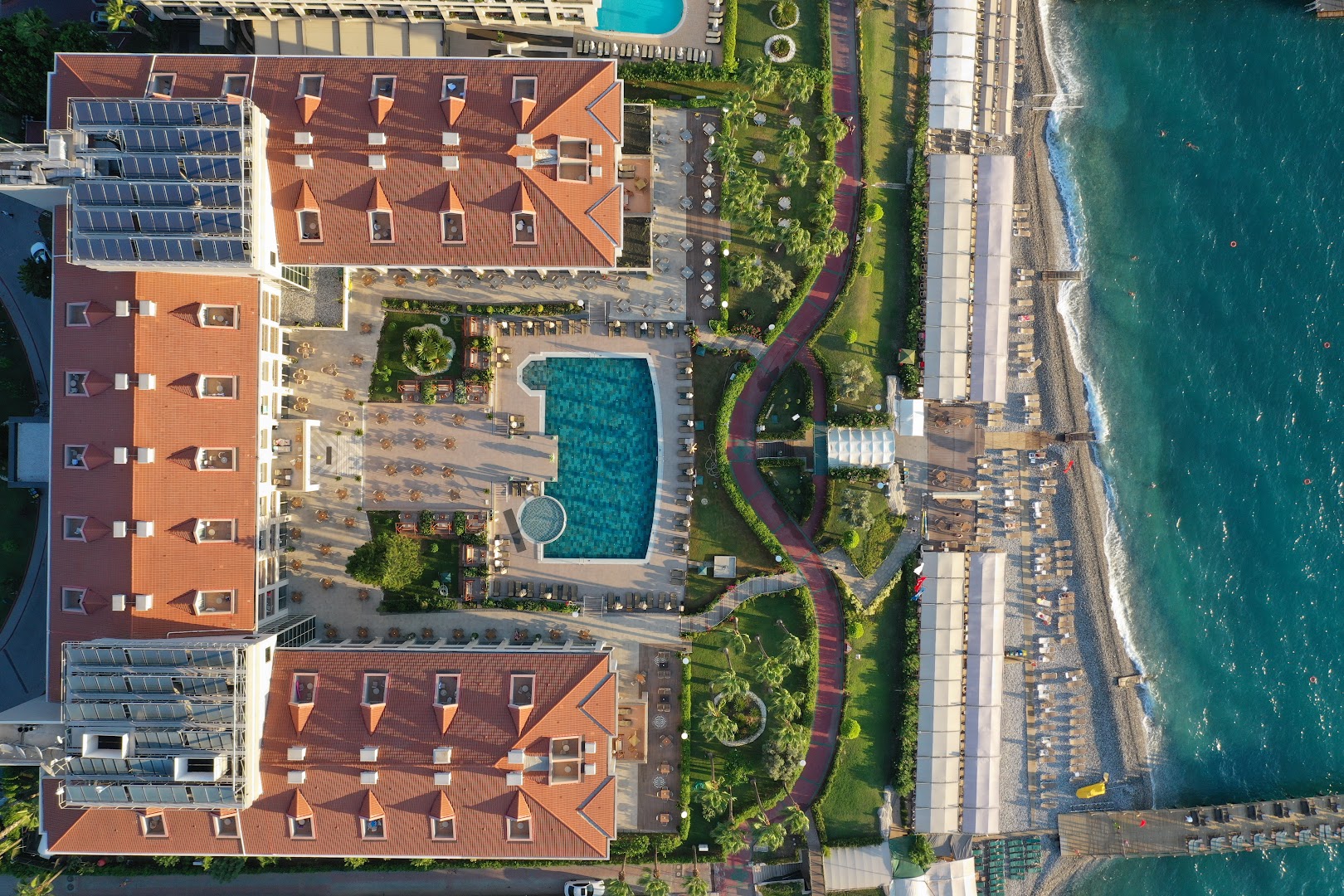 Fame Residence Kemer & Spa skats no augšas uz viesnīcas teritoriju, baseinu, dārza celiņiem un privāto pludmales zonu pie jūras