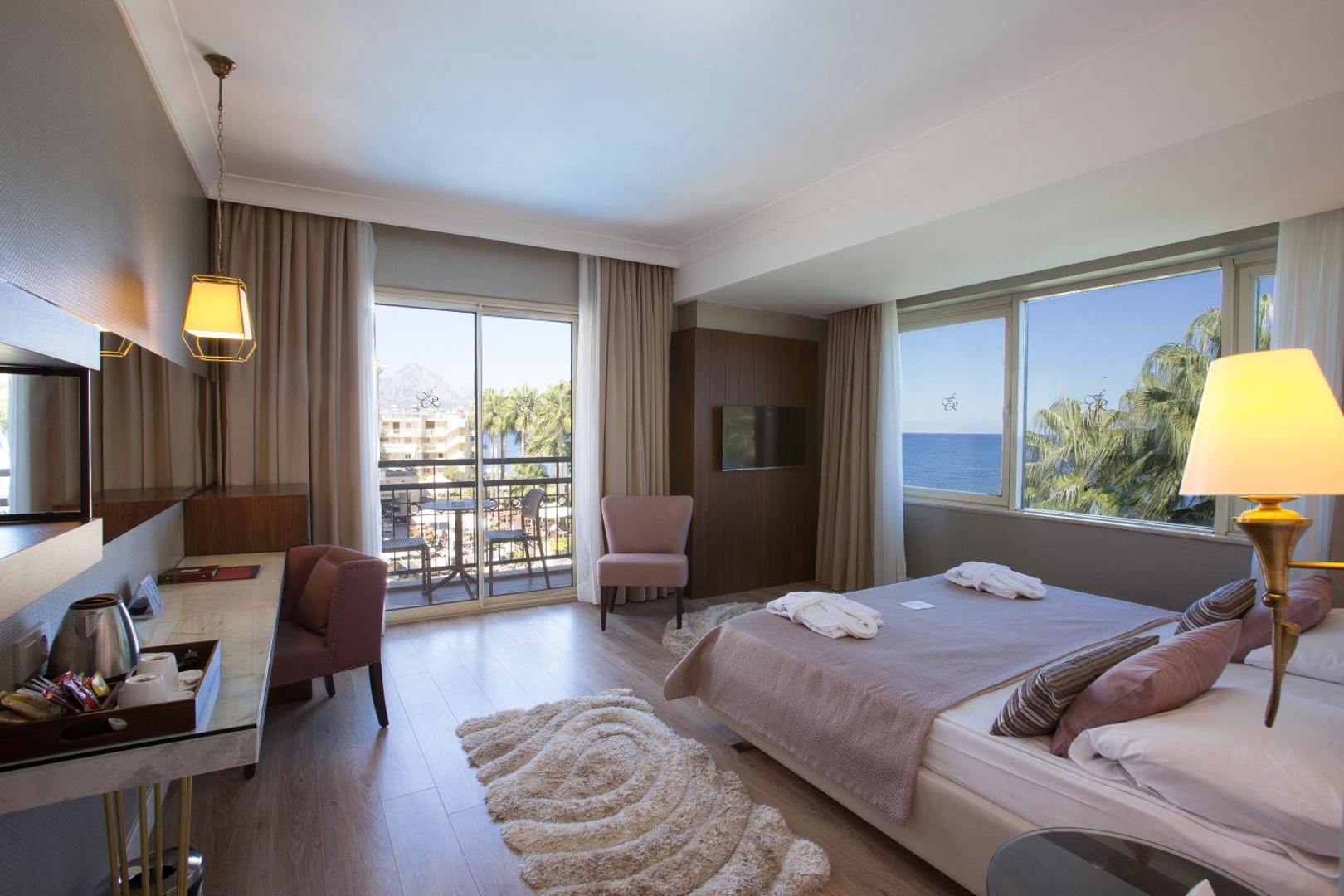 Fame Residence Kemer & Spa numurs ar skatu uz jūru, balkonu, lieliem logiem un gaišu interjeru Kemeras kūrortā Turcijā