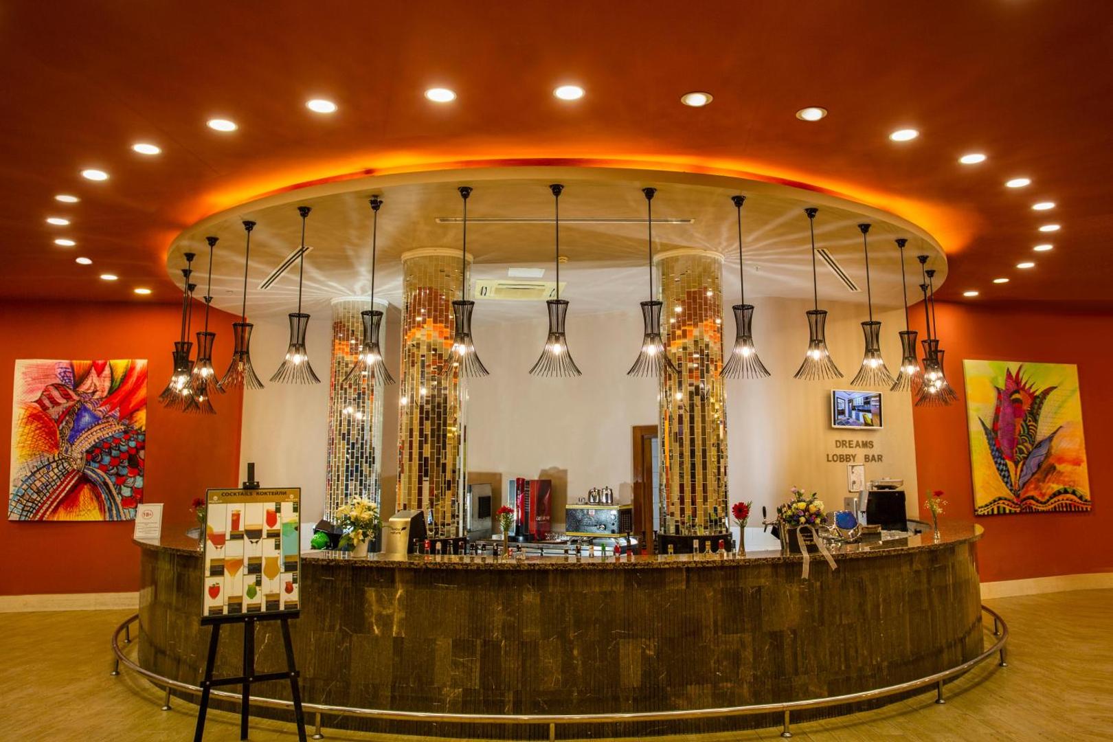 Sherwood Exclusive Lara viesnīcas Dreams Lobby Bar ar modernu apgaismojumu, mozaīkas kolonnām un plašu dzērienu izvēli Antalijā