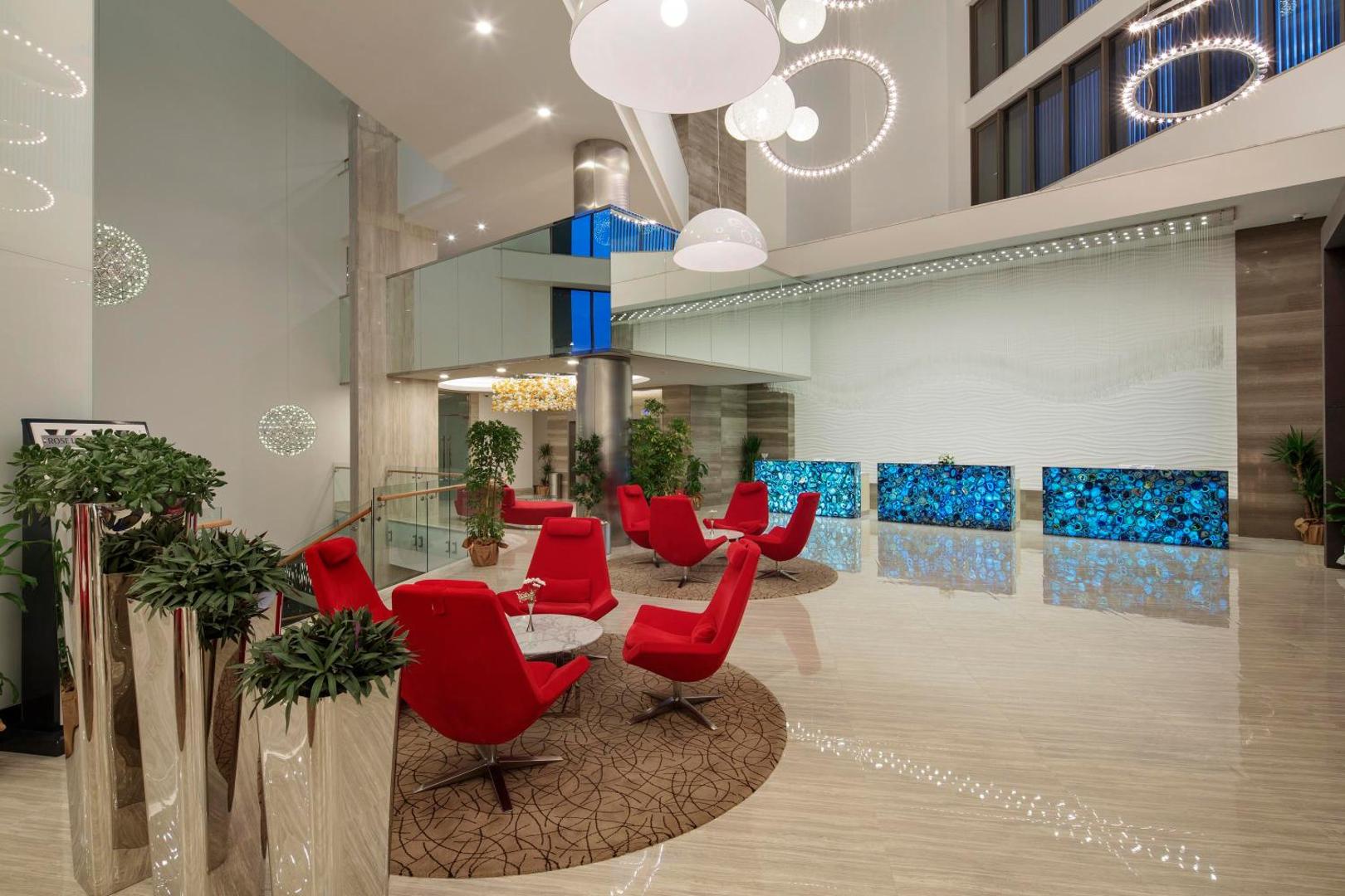 The Sense Deluxe recepcijas zona ar unikālām zila akmens letēm, sarkaniem dizaina krēsliem un modernu, gaišu interjeru
