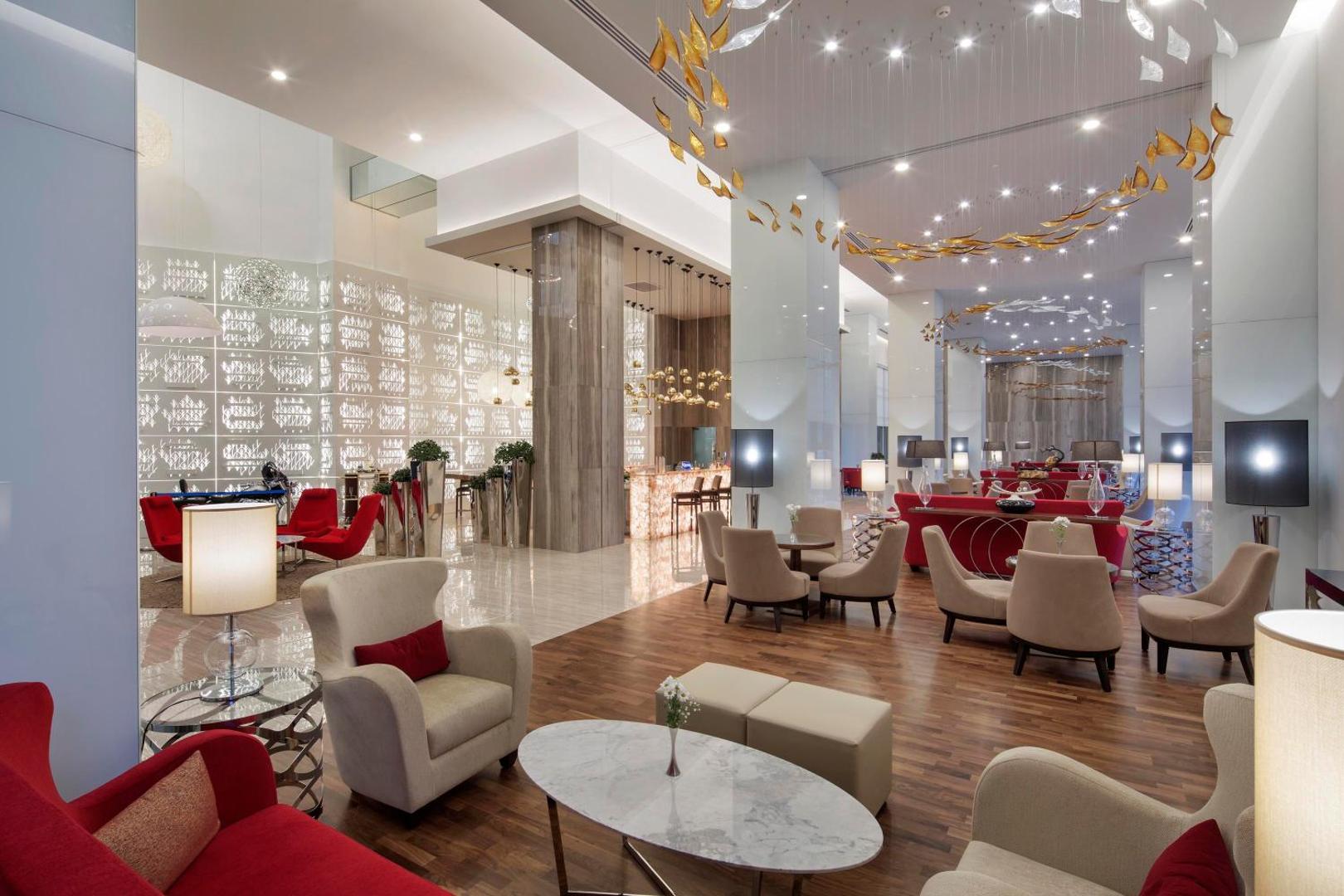 The Sense Deluxe viesnīcas modernais lobby bārs un atpūtas zona ar augstiem griestiem, dizaina gaismekļiem un ērtiem atpūtas krēsliem