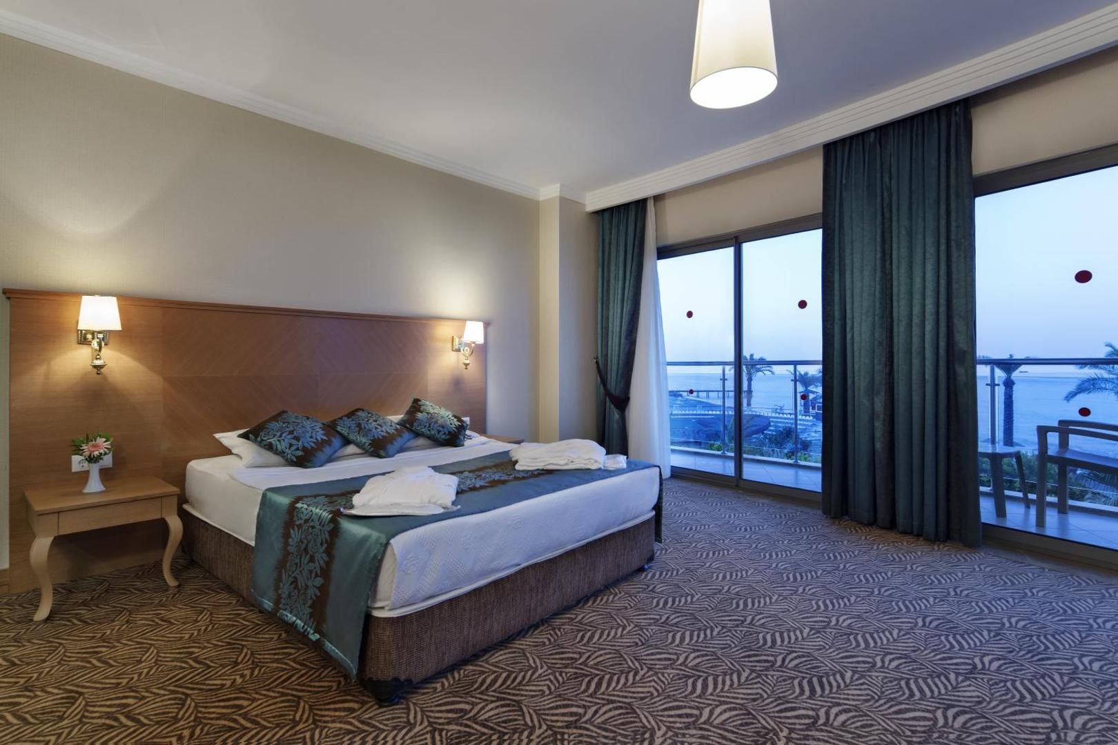 Saphir Hotel & Villas luksusa numurs ar lielu gultu, paklāju un plašu balkonu, no kura paveras tiešs skats uz jūru