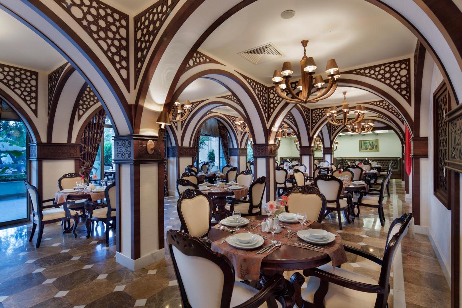 Saphir Hotel & Villas restorāns ar greznu austrumu stila interjeru, koka arkām un eleganti klātiem apaļajiem galdiem vakariņām