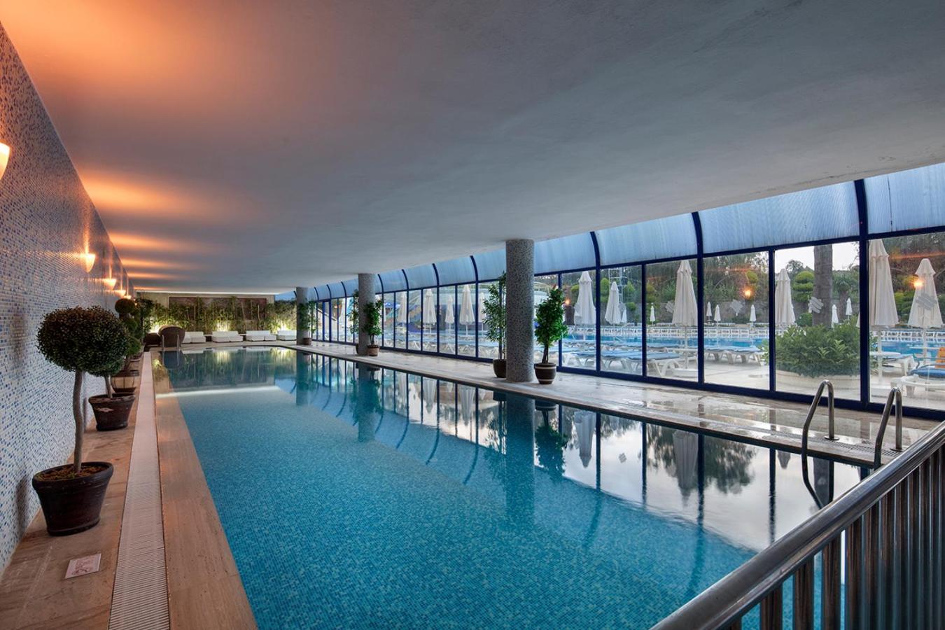 Saphir Hotel & Villas iekštelpu baseins ar panorāmas logiem uz dārzu un atpūtas krēsliem relaksācijas zonā