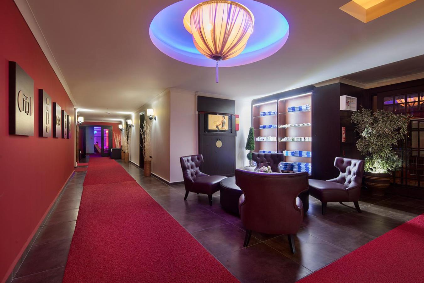 Saphir Hotel & Villas spa centra atpūtas zona ar sarkaniem paklājiem, ērtiem krēsliem un austrumnieciska stila gaismekļiem.
