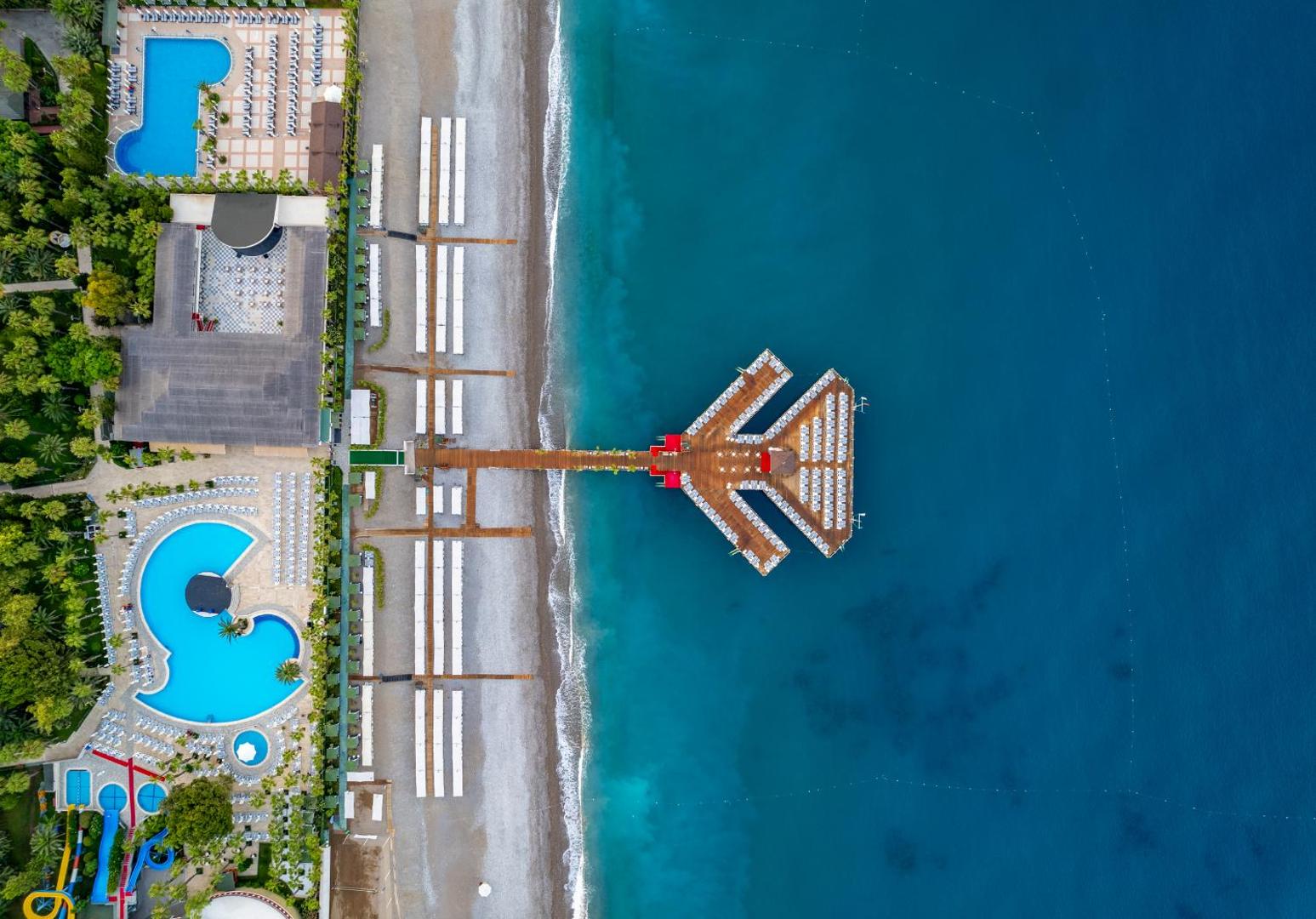 Botanik Hotel & Resort aerofoto ar privāto pludmali, unikālas formas koka piestātni un baseiniem piekrastē