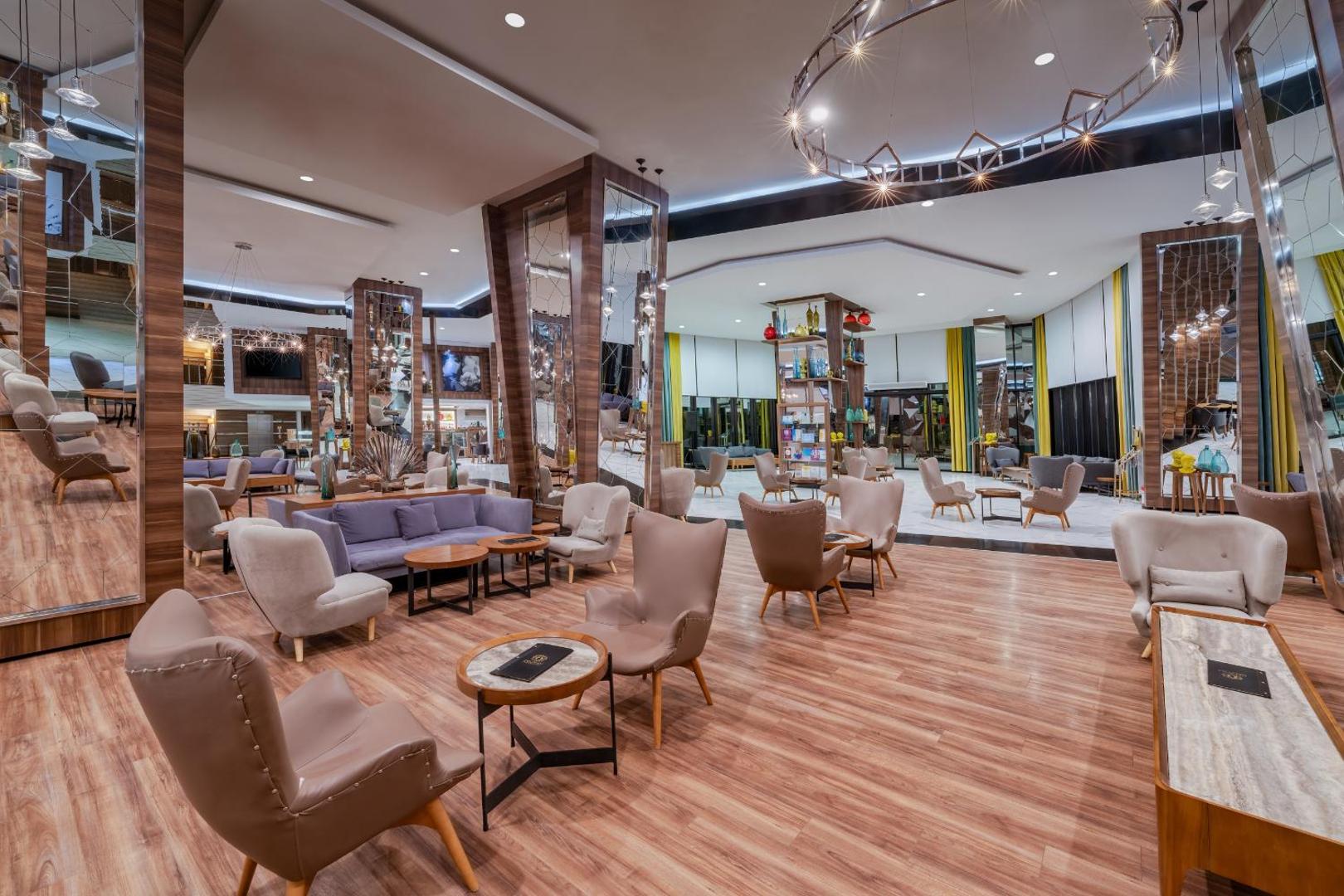Botanik Hotel & Resort plašais lobby bārs ar moderniem atpūtas krēsliem, koka apdari un spoguļu kolonnām viesnīcas galvenajā ēkā
