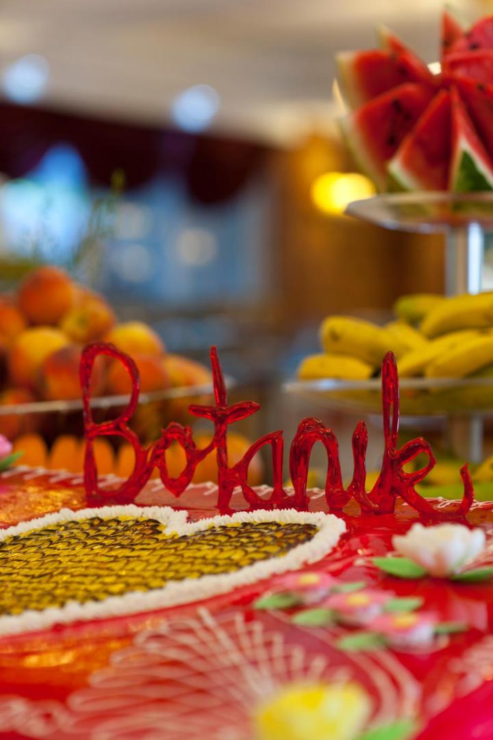 Botanik Hotel & Resort svētku torte ar uzrakstu Botanik un svaigiem augļiem viesnīcas restorānā