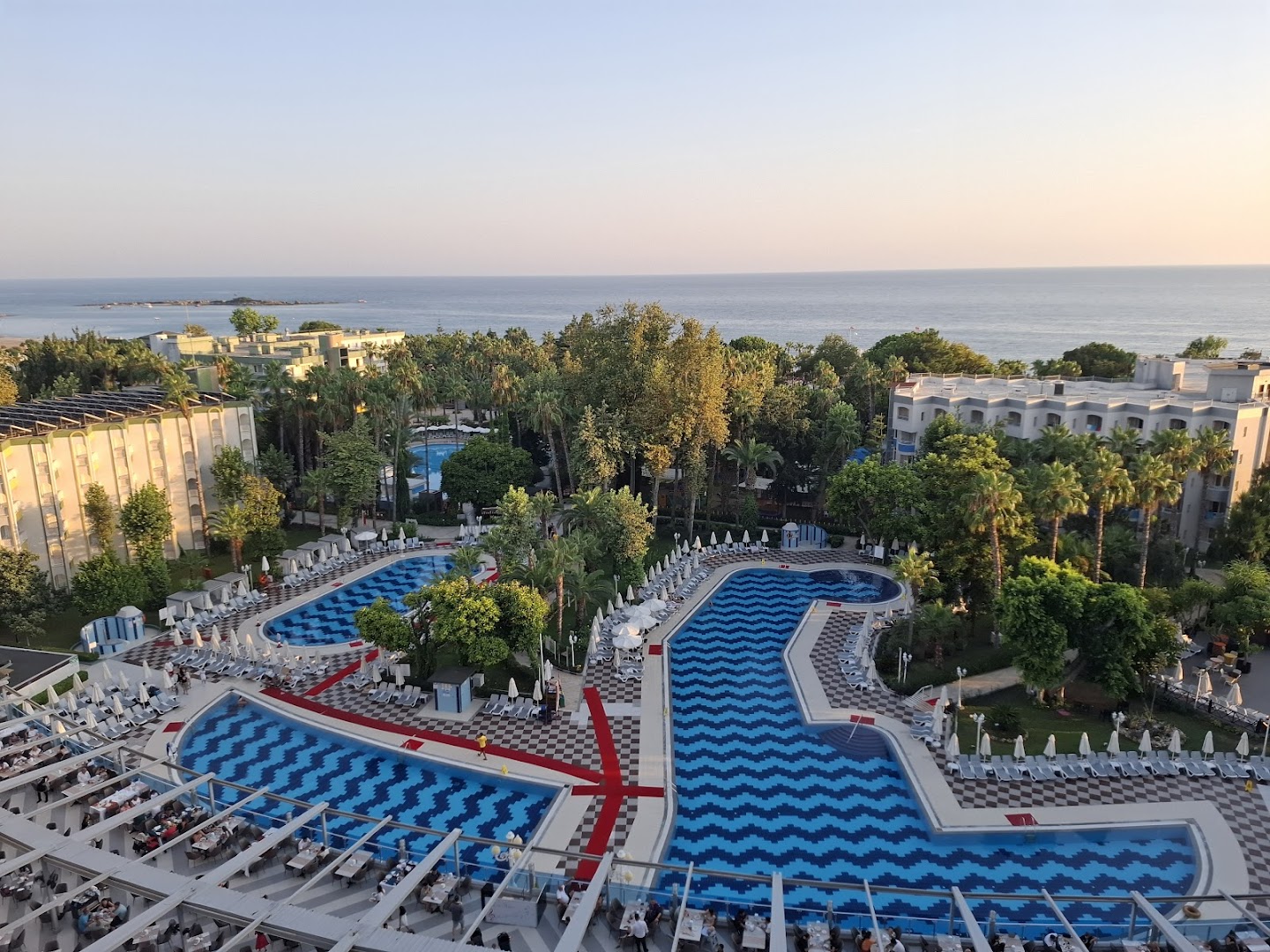 Botanik Hotel & Resort skats no augšas uz plašo baseinu kompleksu un Vidusjūras piekrasti Alanjas reģionā saulrieta laikā