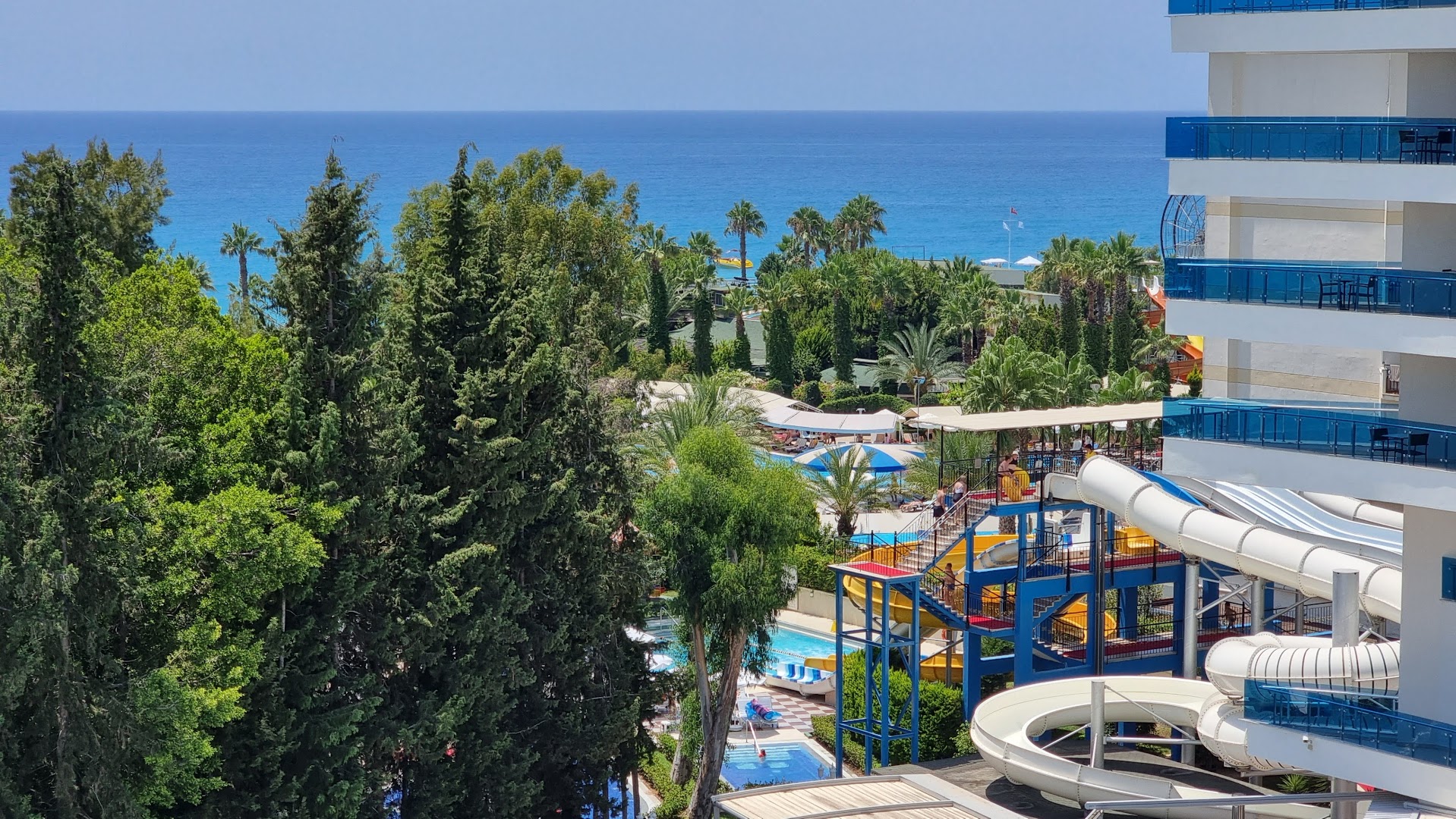Skats no Botanik Hotel & Resort balkona uz akvaparku, palmām un zilo Vidusjūru Alānijas piekrastē