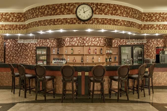 Botanik Hotel & Resort iekštelpu bārs ar klasisku koka apdari, augstajiem krēsliem un plašu dzērienu izvēli pie bāra letes
