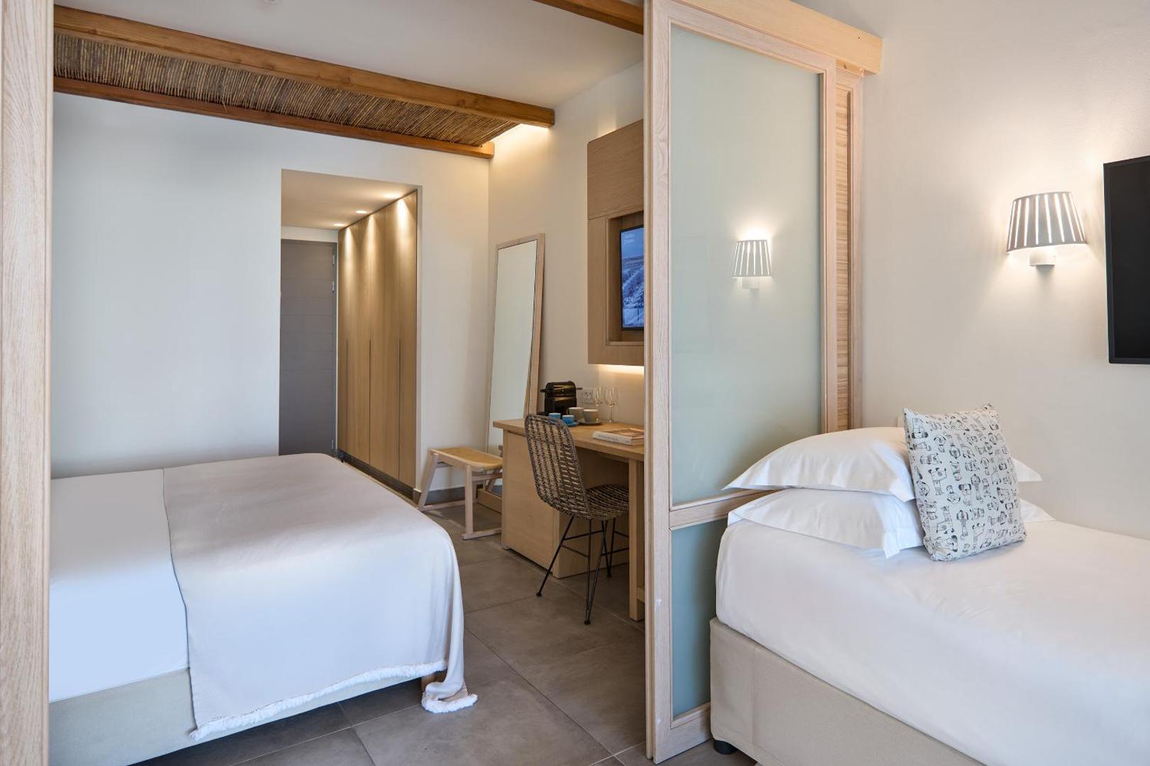 Atlantica Dreams Resort ģimenes numura interjers ar divām atsevišķām guļamzonām, ko atdala bīdāmas durvis un gaiša koka apdare.