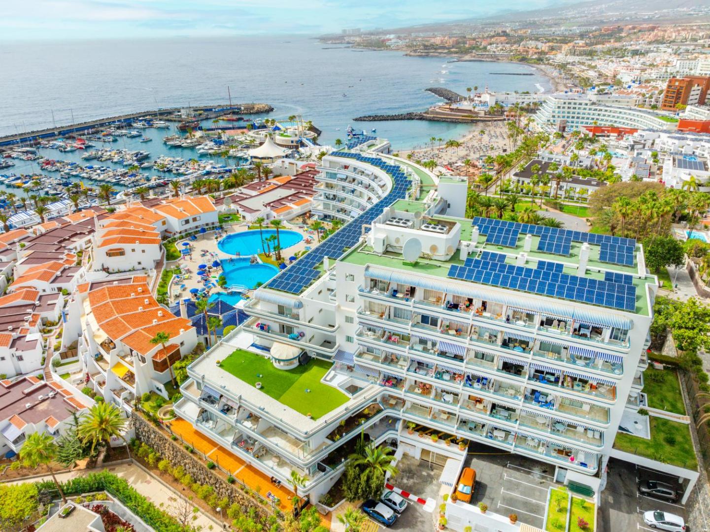 Hovima Atlantis viesnīcas ēka no putna lidojuma Tenerifē — skats uz jahtu piestātni, okeānu un baseinu zonu Costa Adeje kūrortā