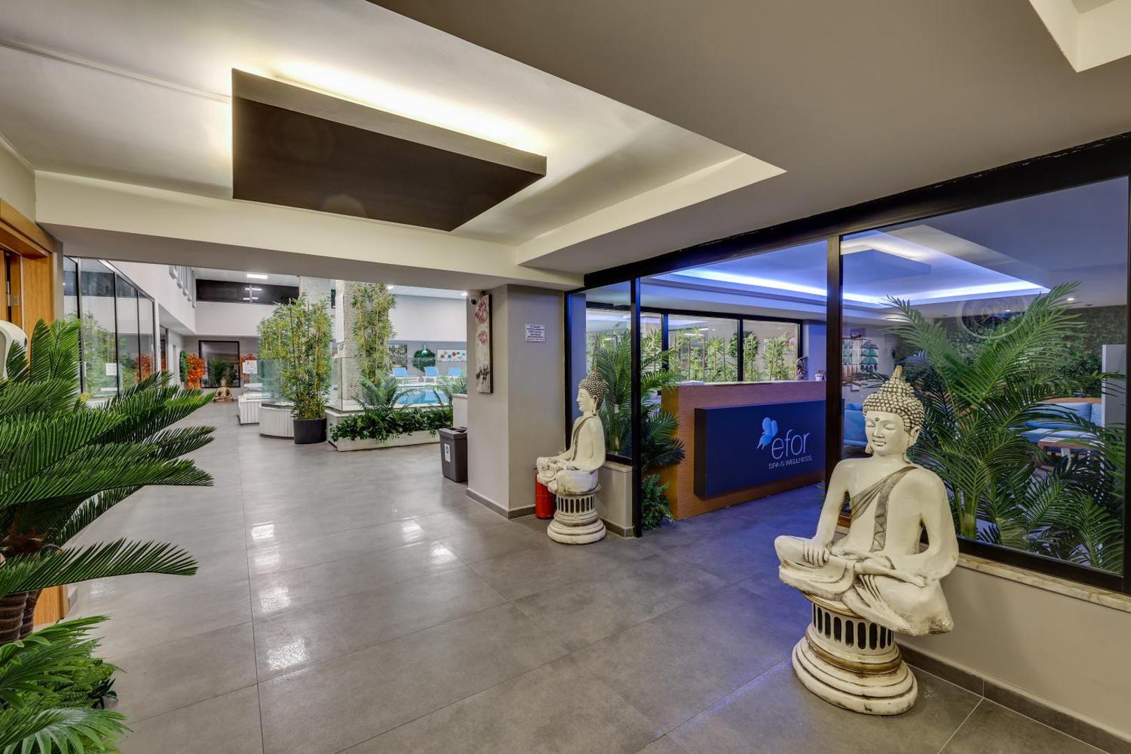 Diamond of Bodrum Hotel spa centra ieeja ar Budas statujām, telpaugiem un gaišu interjeru, vedot uz relaksācijas zonu