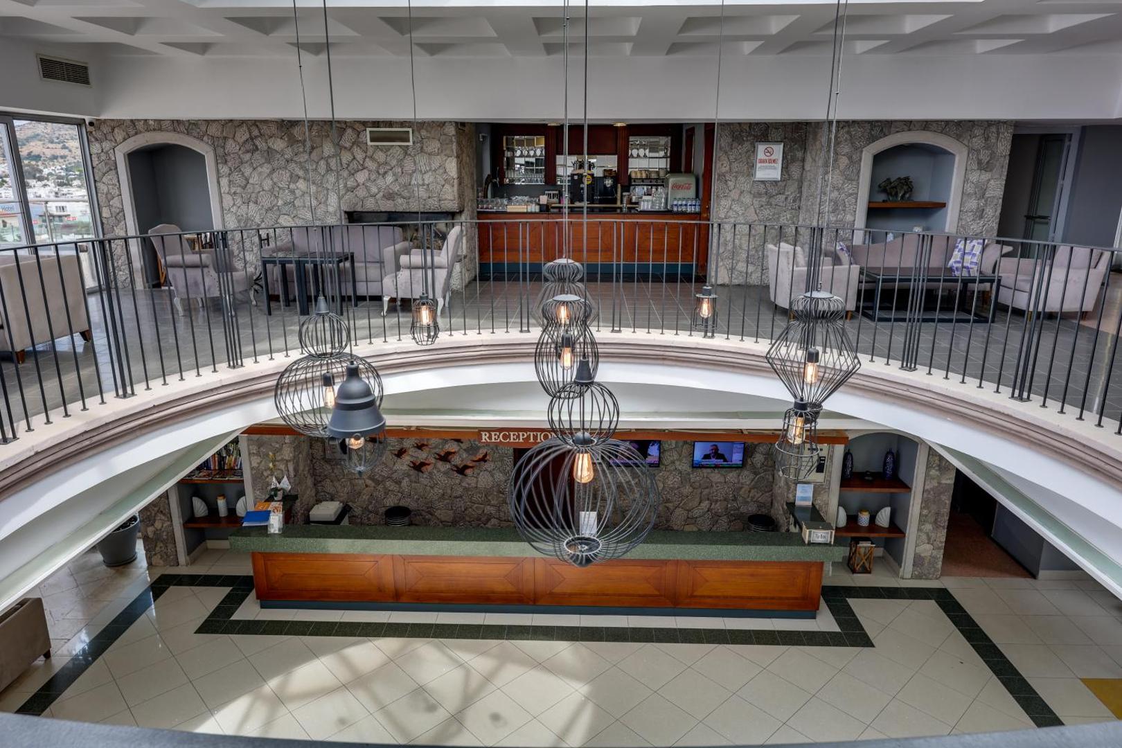 Diamond of Bodrum Hotel vestibils ar skatu uz recepcijas galdu un lobby bāru augšstāvā, akmens sienu apdare un dizaina gaismekļi