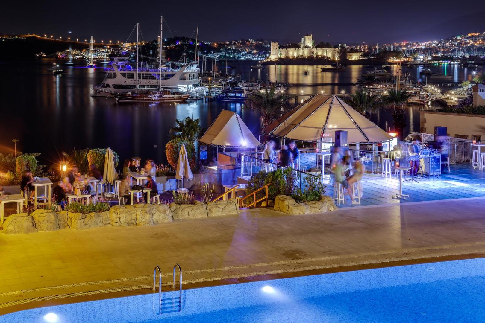 Diamond of Bodrum Hotel bāra zona vakarā ar skatu uz izgaismoto Bodrumas cietoksni un ostā pietauvotajām jahtām.