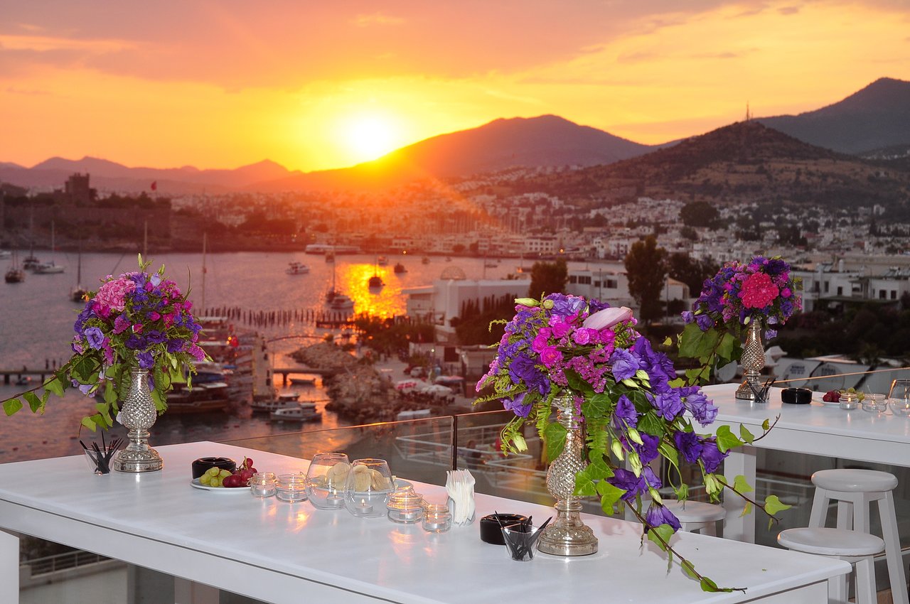 Diamond of Bodrum Hotel jumta terase saulrieta laikā ar skatu uz Bodrumas līci, jahtām un vēsturisko cietoksni Turcijā