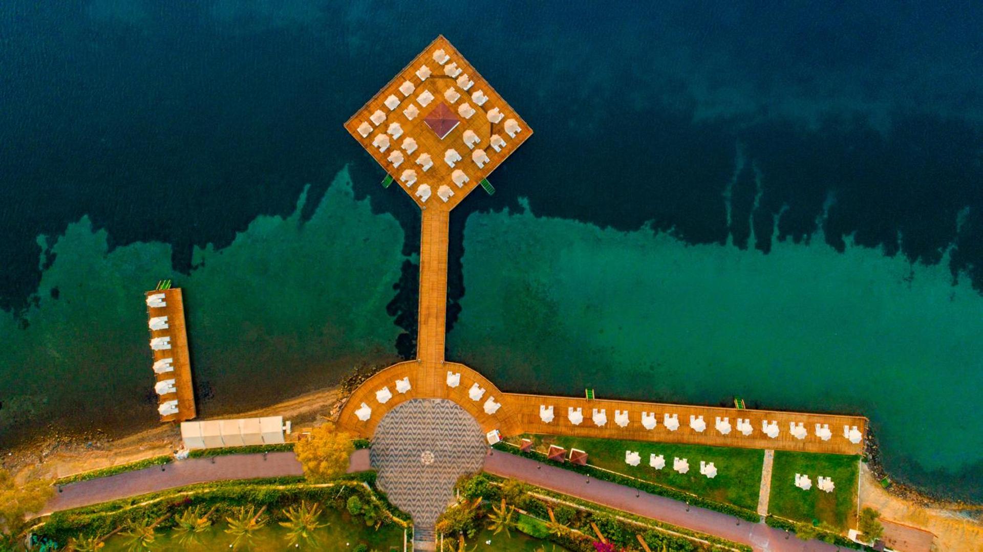 Aerofoto skats uz Hotel Baia Bodrum unikālo koka piestātni un sauļošanās zonu tirkīzzilā Egejas jūras ūdenī