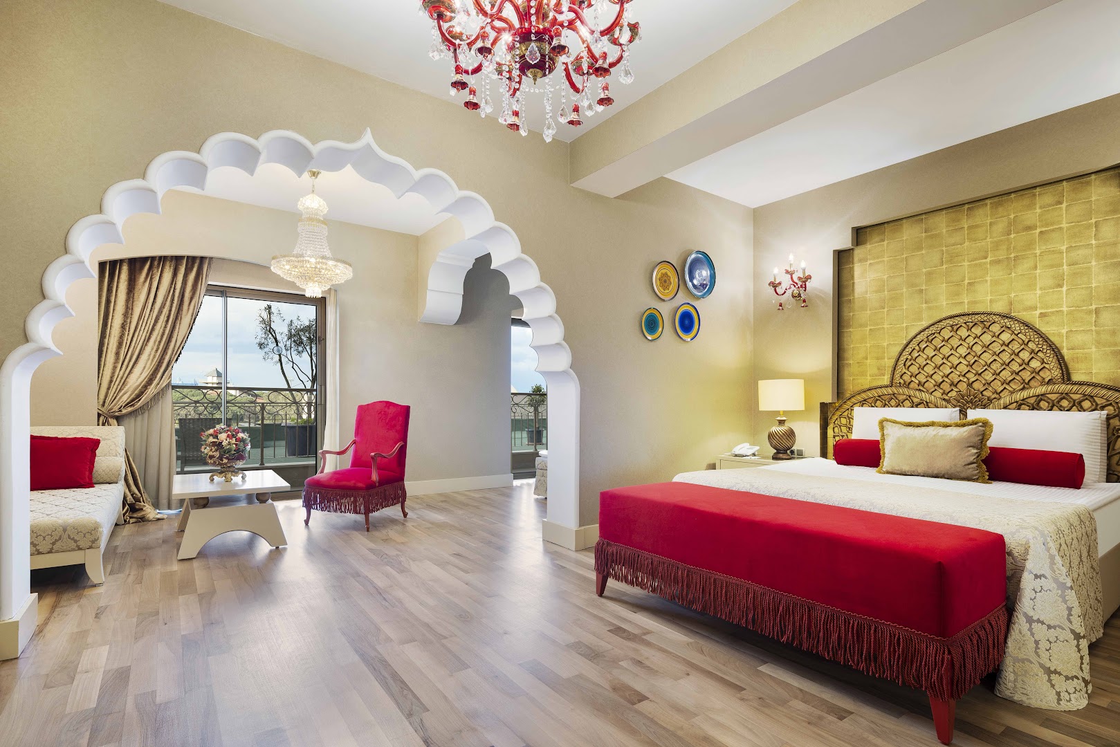 Spice Hotel & Spa grezns numurs ar austrumu stila arkām, sarkanu samta gultu, kristāla lustru un balkonu ar skatu uz dārzu.
