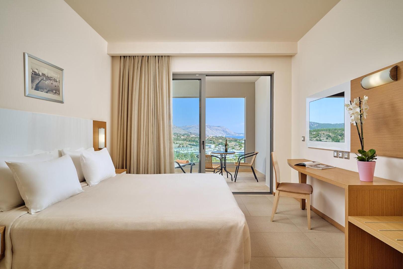 Princess Sun Hotel numurs ar balkonu, no kura paveras panorāmas skats uz Rodas piekrasti un kalniem