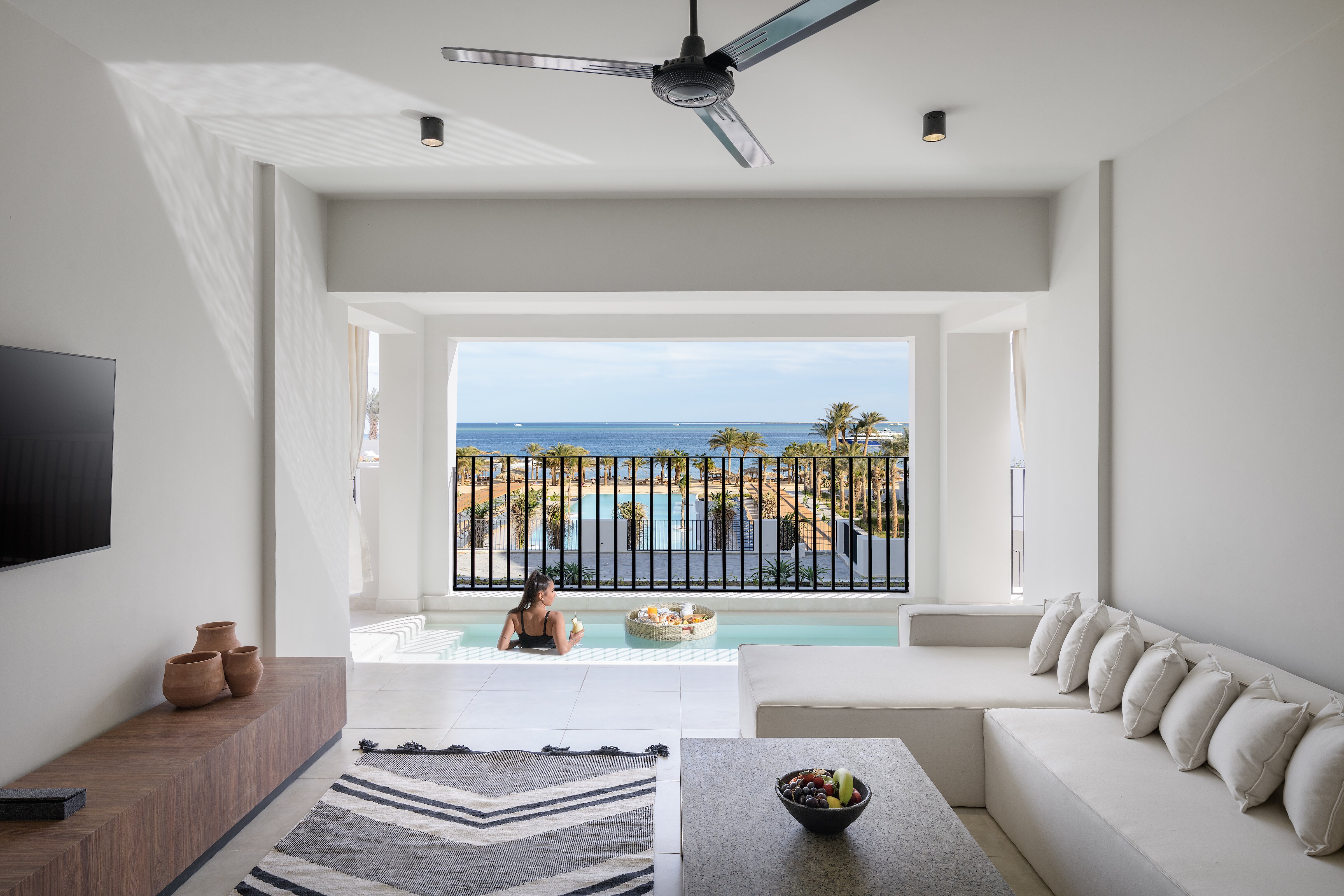 Serry Beach Resort numurs ar privātu baseinu uz terases, skatu uz jūru un palmu dārzu Hurgadā, Ēģiptē — gaišs interjers ar dīvānu.