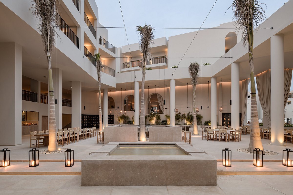 Serry Beach Resort iekšpagalms ar dekoratīvu baseinu, palmām un restorāna zonu — moderna minimālisma arhitektūra un vakara apgaismojums