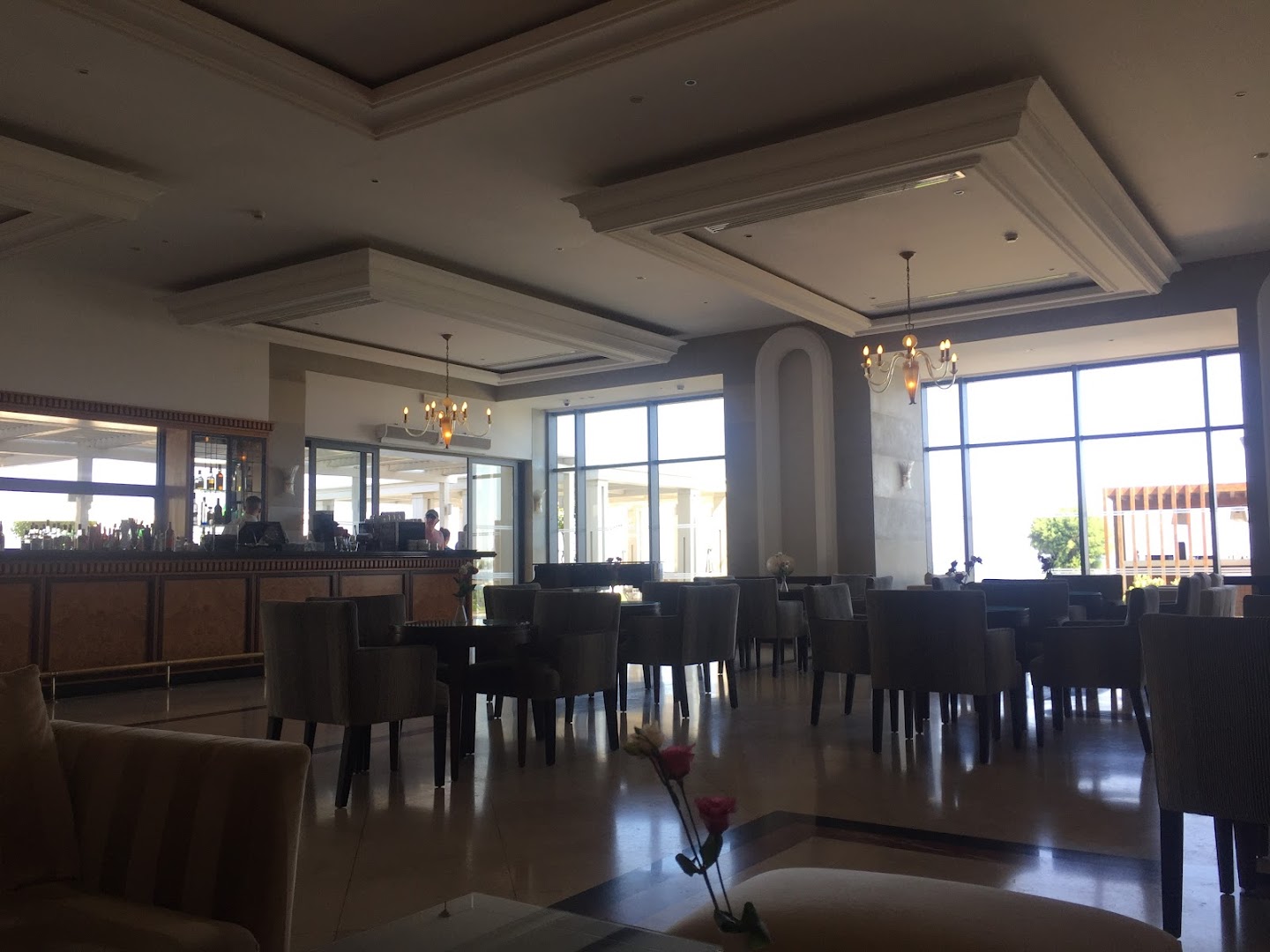 Electra Palace viesnīcas lobby bārs ar plašiem logiem, klasiskām mēbelēm un lustrām — skats uz terasi un piekrasti